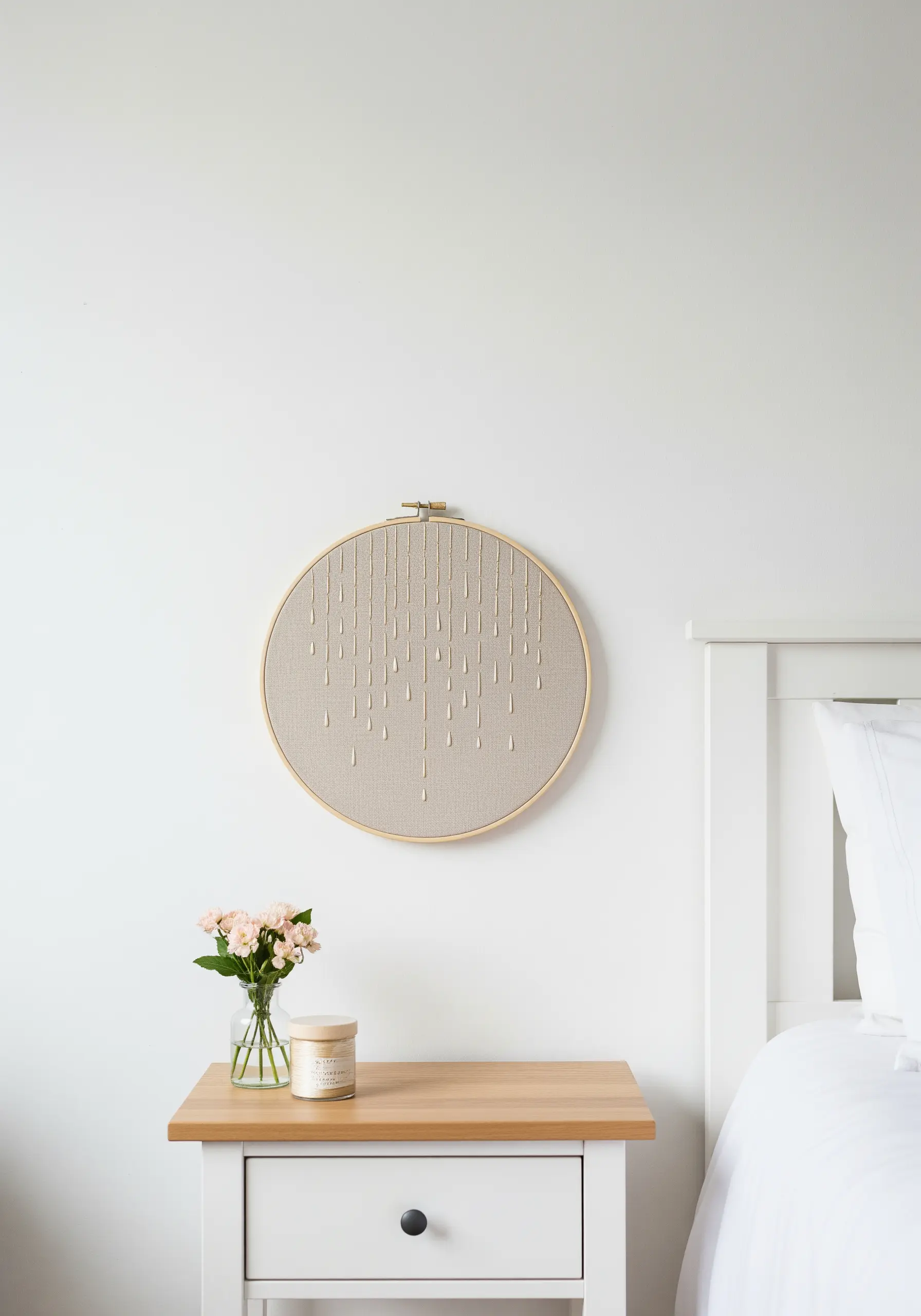An embroidery hoop with vertical lines of gold detached chain stitches resembling falling rain.