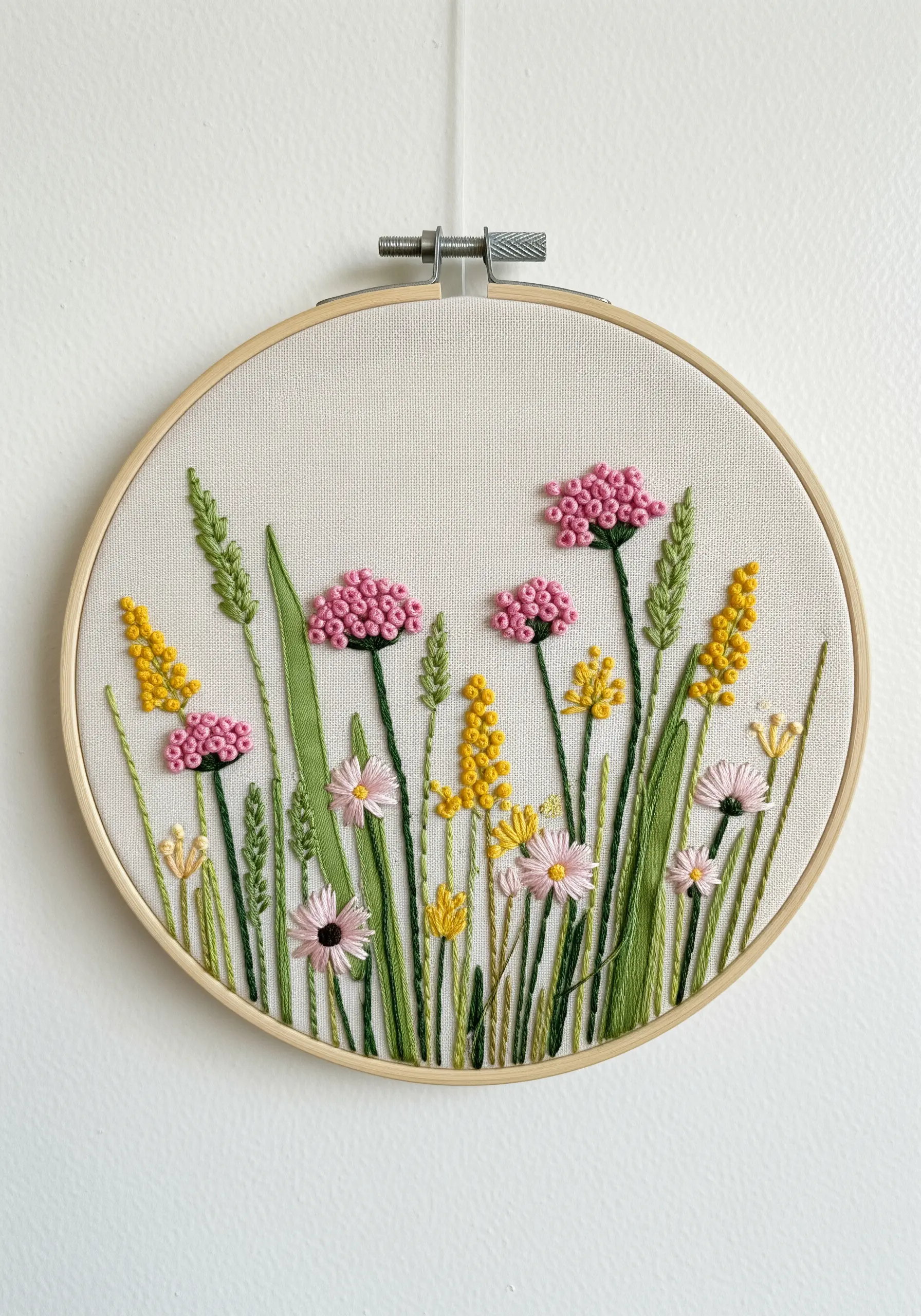 A soft, impressionistic wildflower scene created with pink and yellow French knots and lazy daisies.