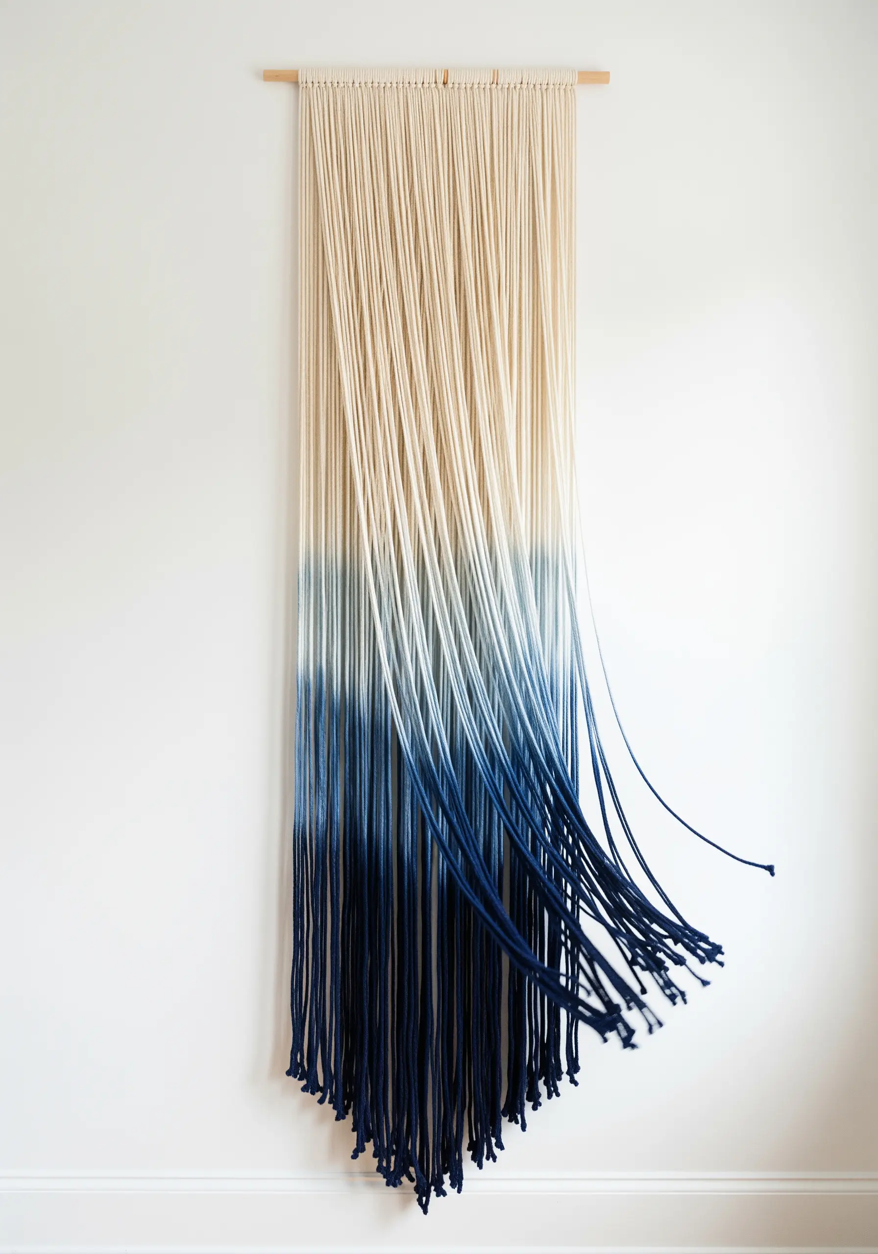 A minimalist wall hanging made of cotton rope dip-dyed with indigo to create an ombré effect.
