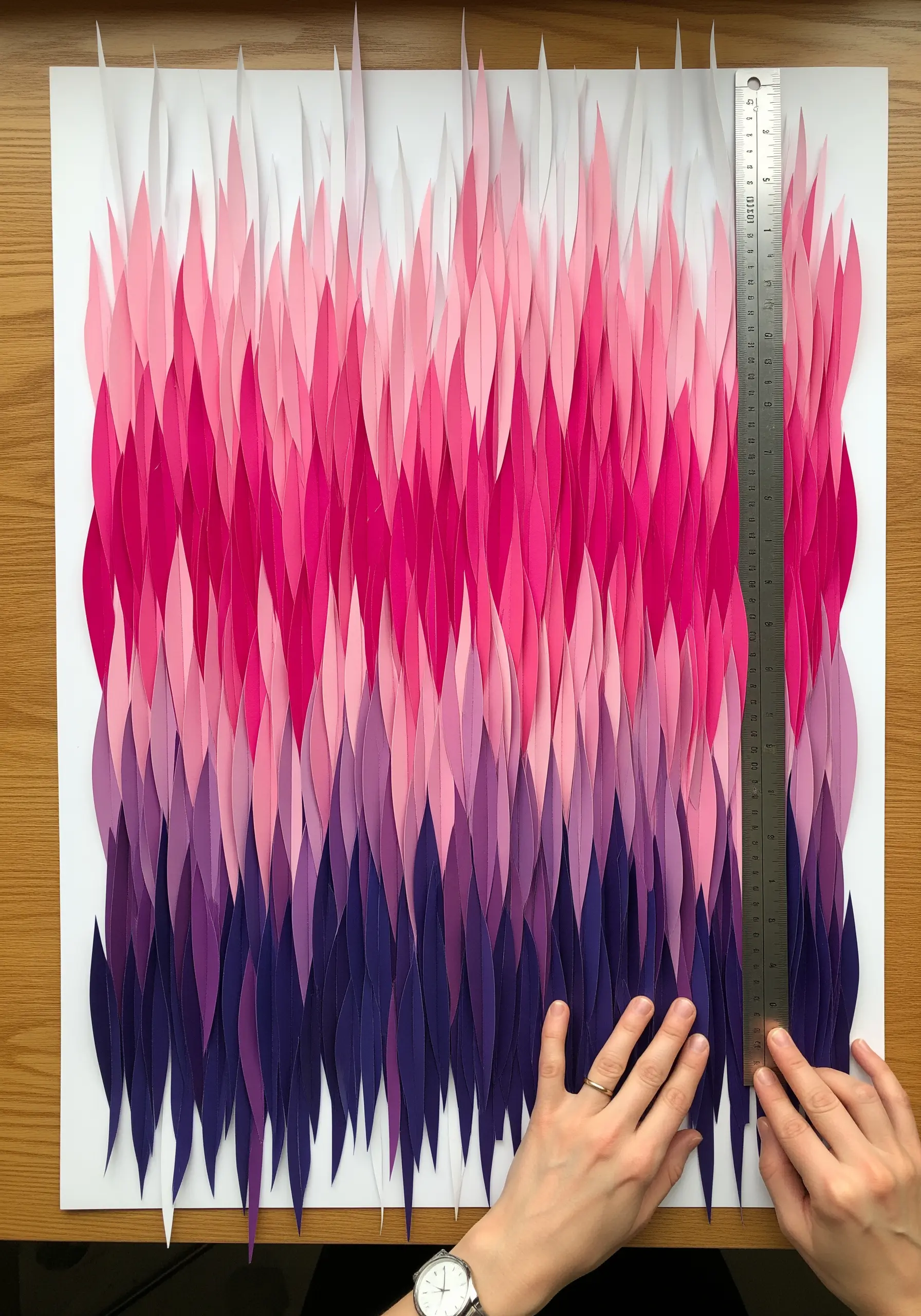 A large-scale paper art piece with vertical strips in a pink-to-purple gradient, creating a curtain effect.