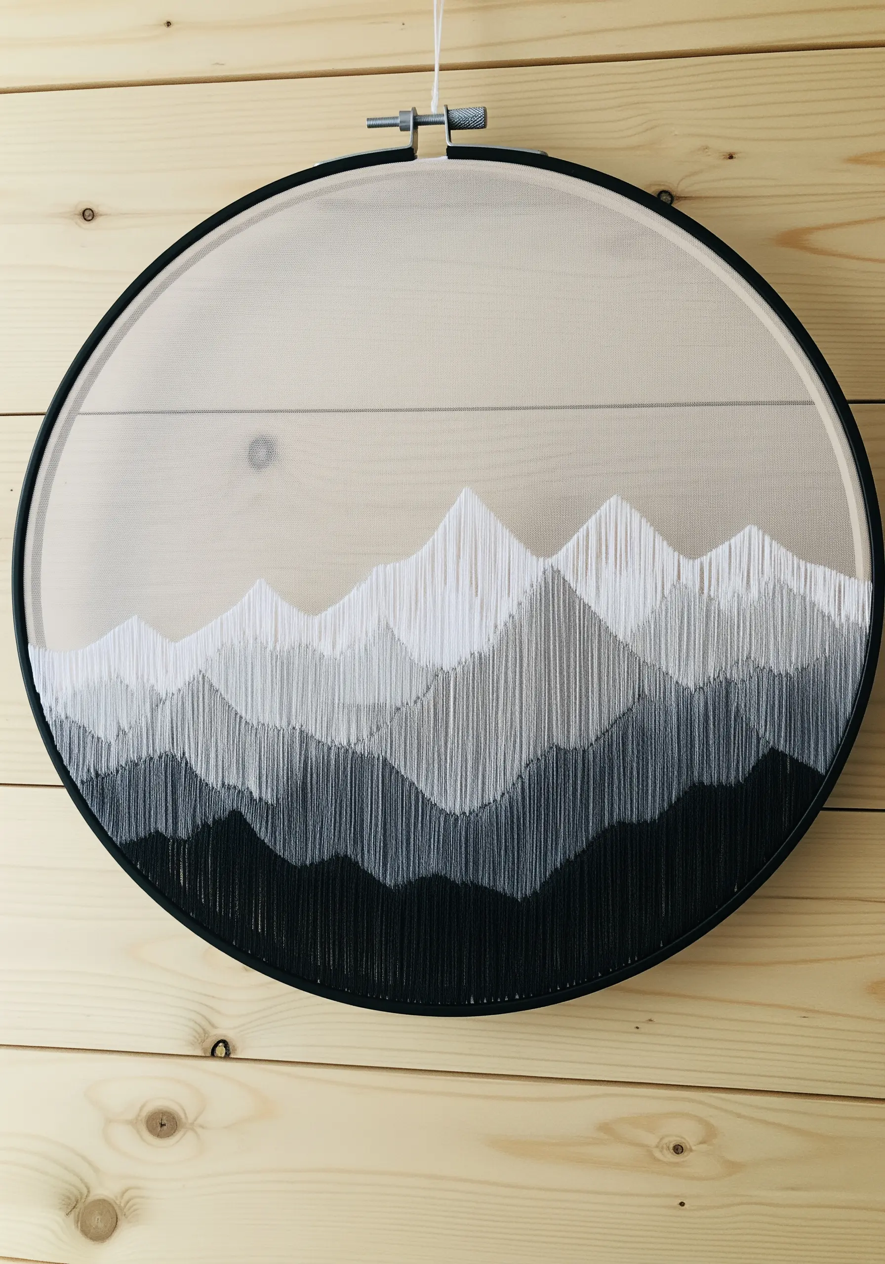 Embroidered mountain range in grayscale on sheer fabric, creating a layered effect.