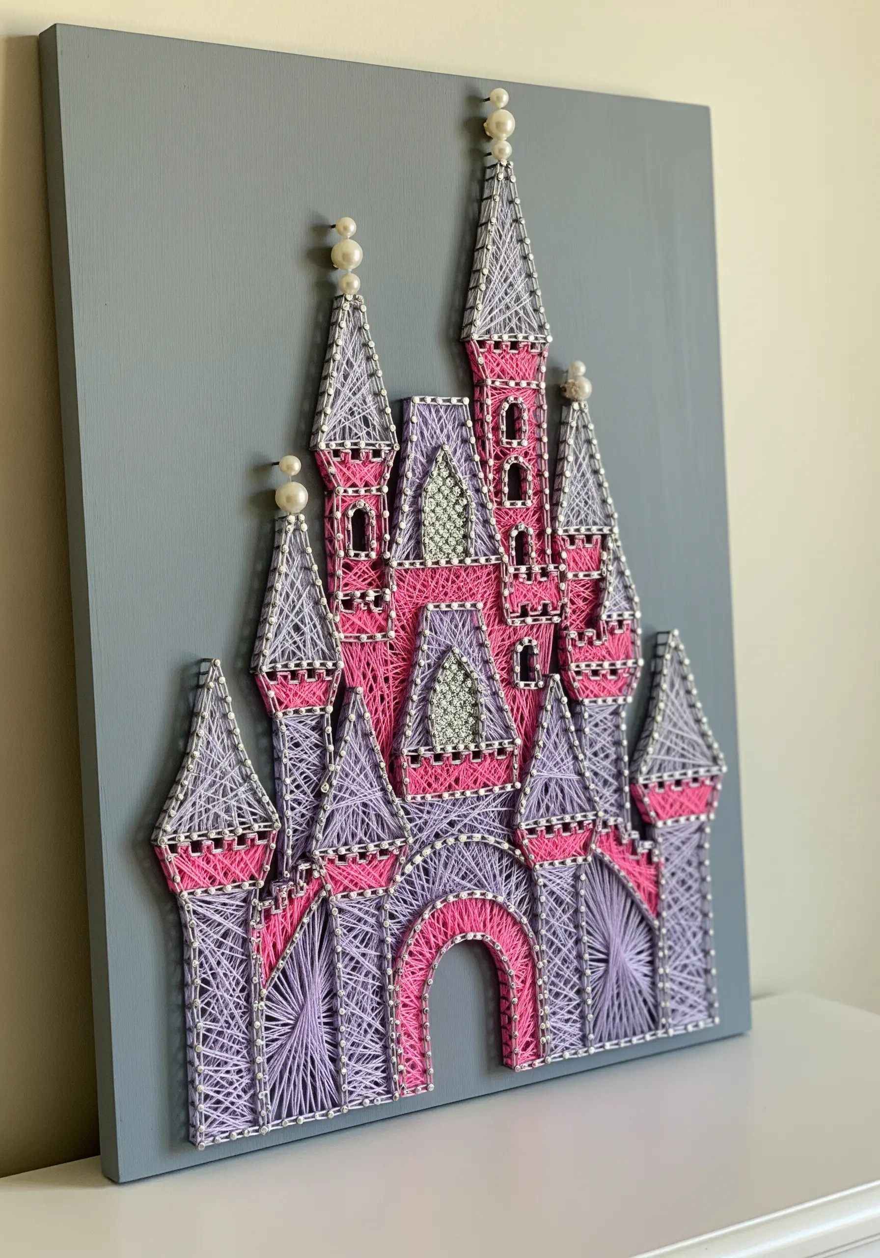 A fairytale castle embroidered with pink and purple thread, using open fills and pearl beads.