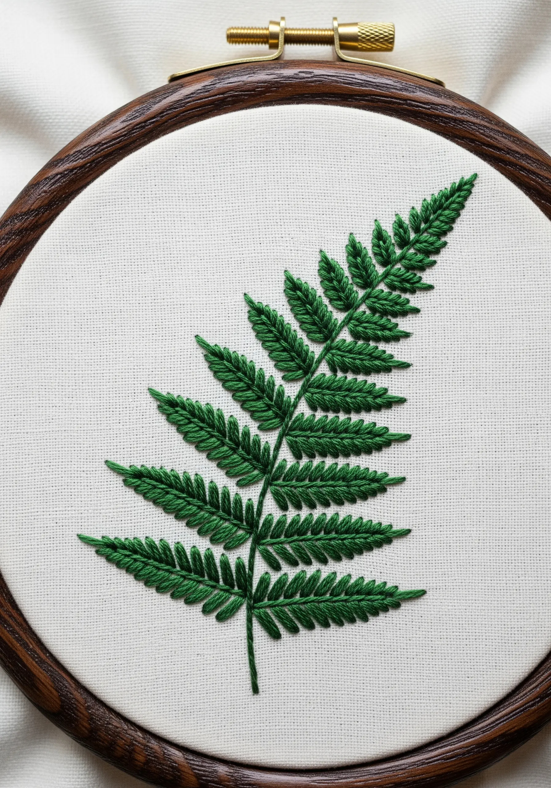 A detailed fern frond embroidered with green fly stitch for the leaves on a central stem.