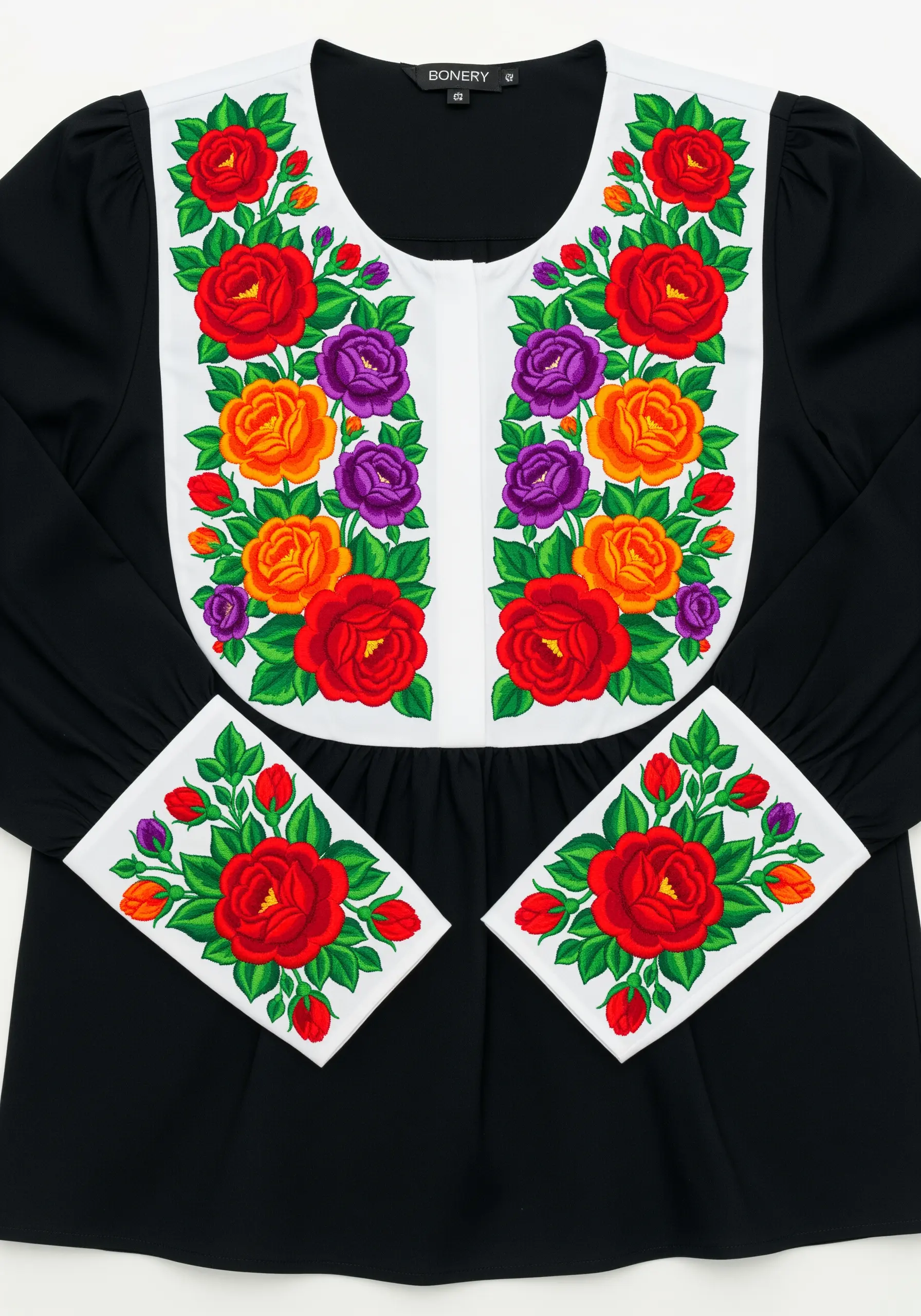 Vibrant, shaded roses in red, purple, and orange embroidered on the white yoke of a black blouse.