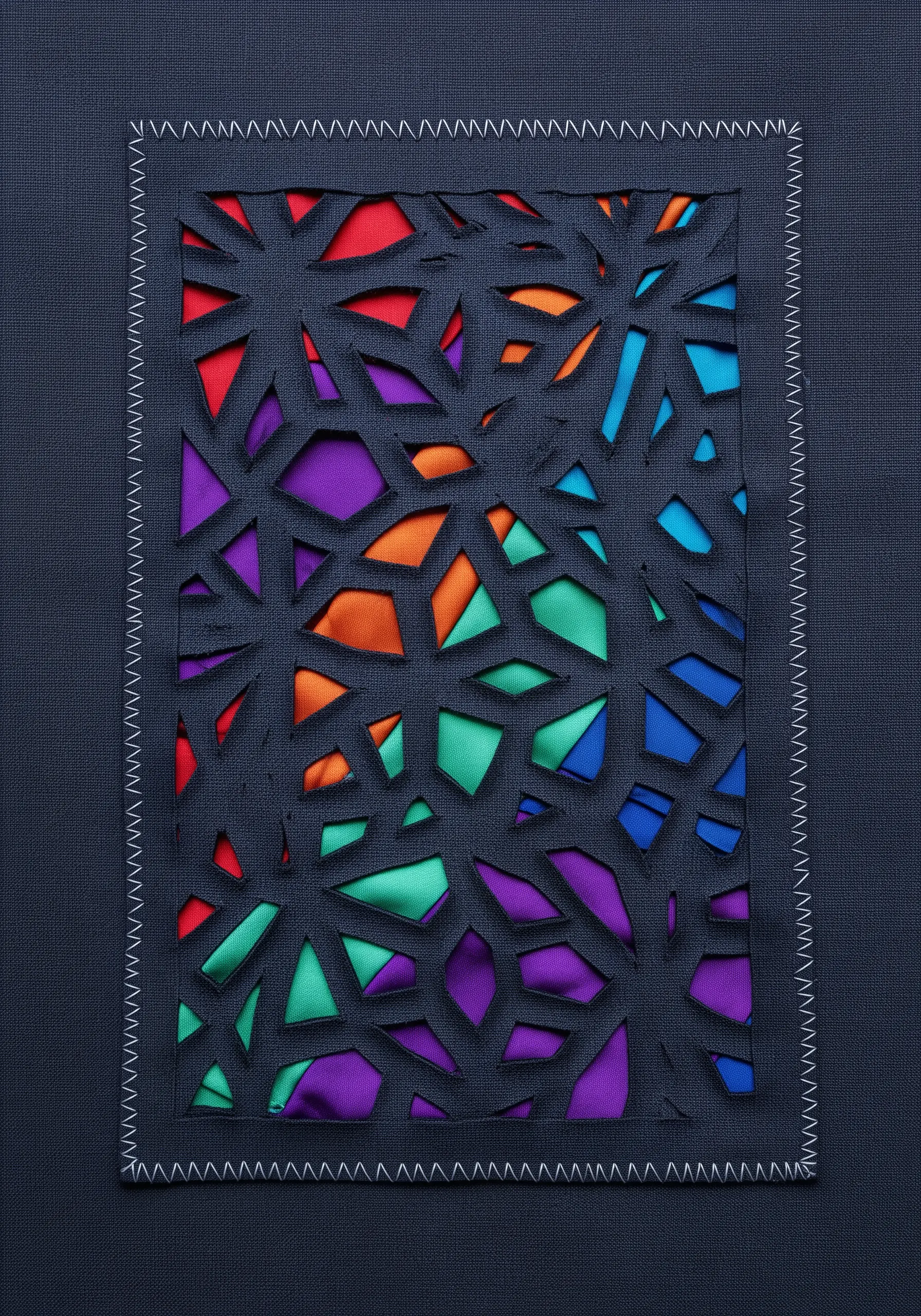 A dark fabric layer with geometric shapes cut out to reveal colorful satin underneath.