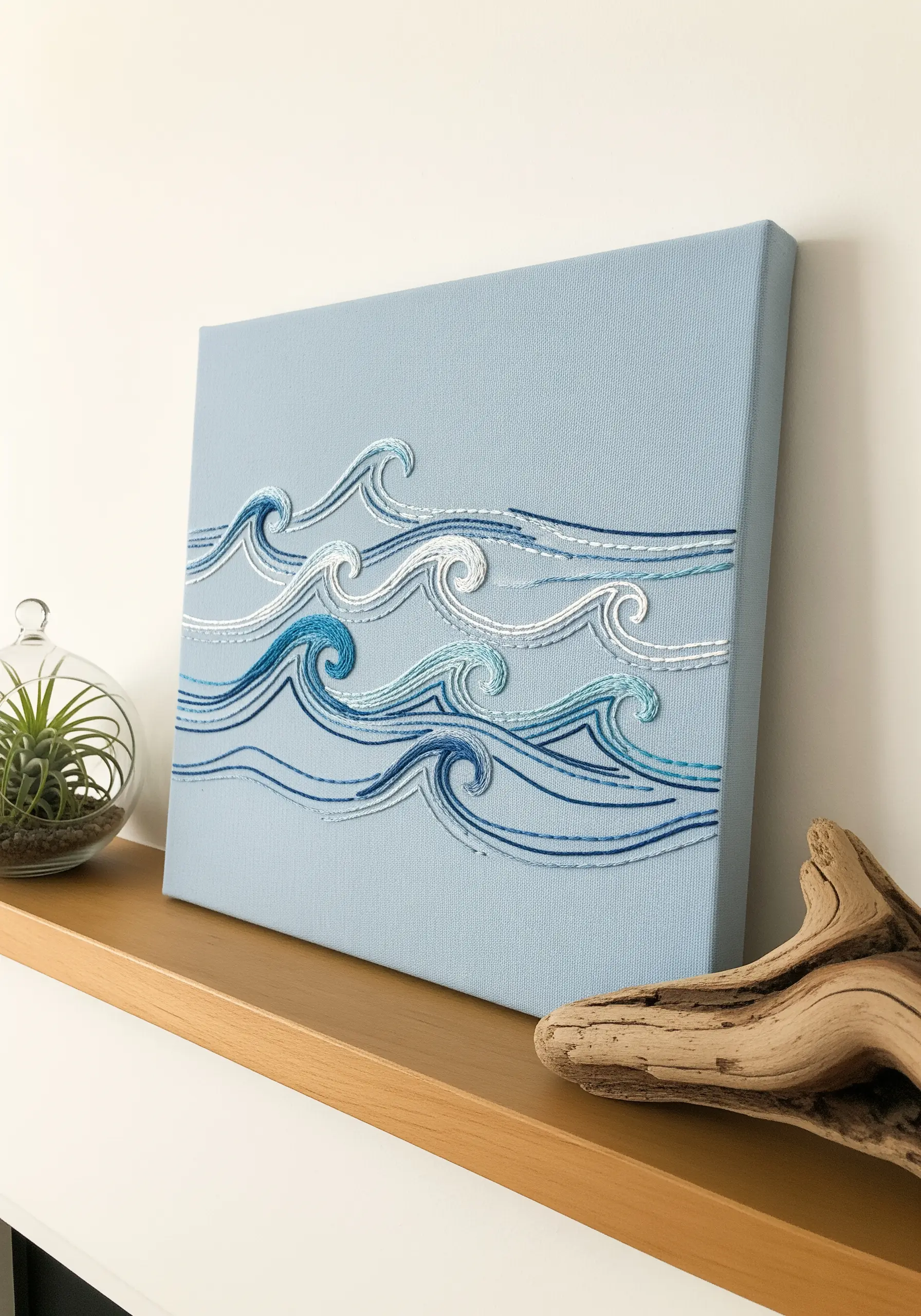 Stylized ocean waves stitched in shades of blue and white on a light blue canvas.