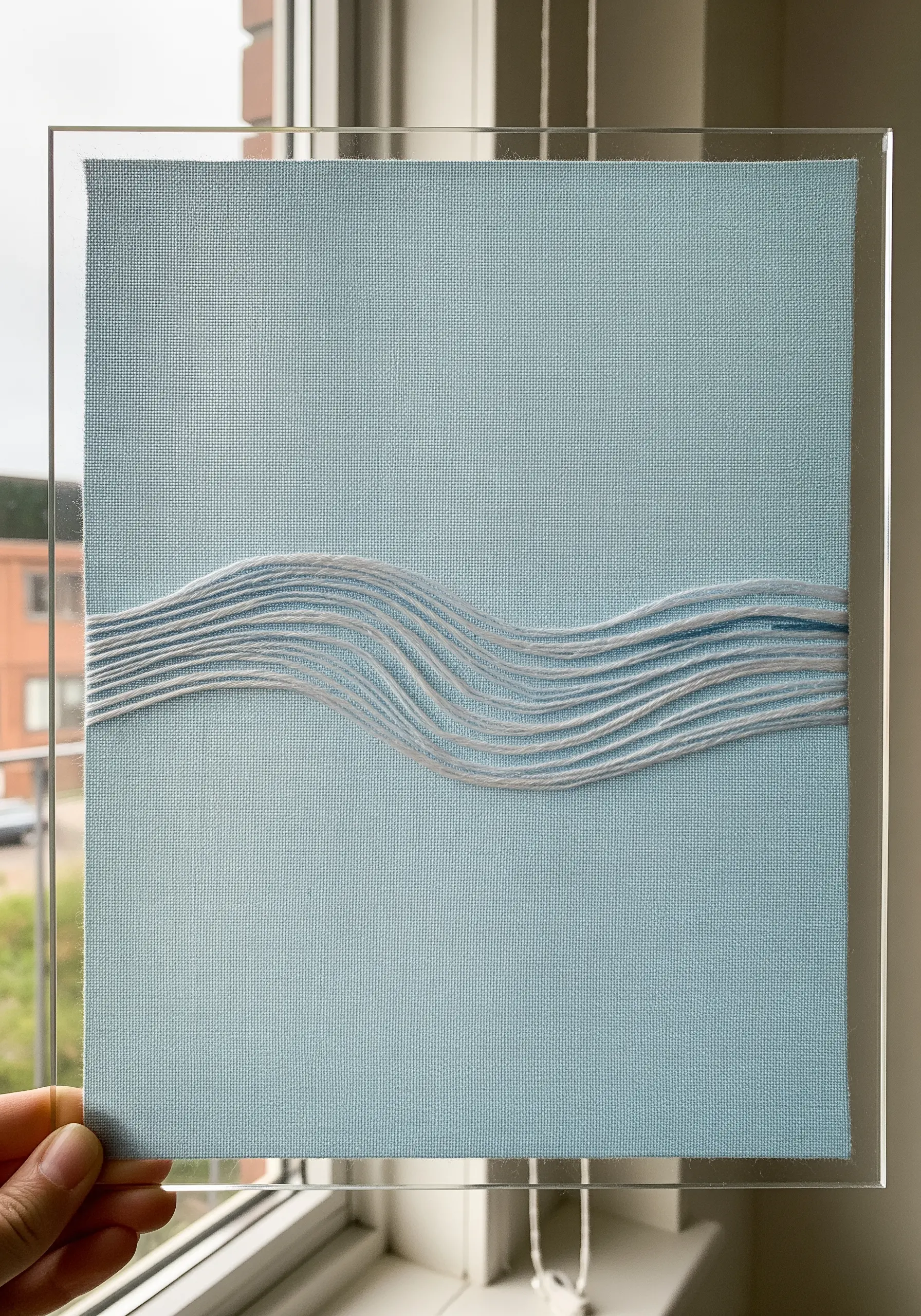 Abstract waves created by wrapping white thread across a light blue canvas.