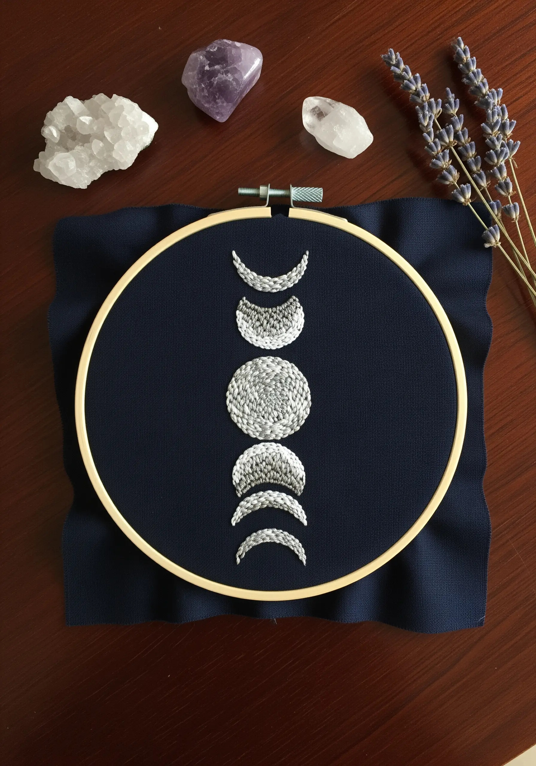 Embroidery of the moon phases created with textured seed stitches on navy fabric