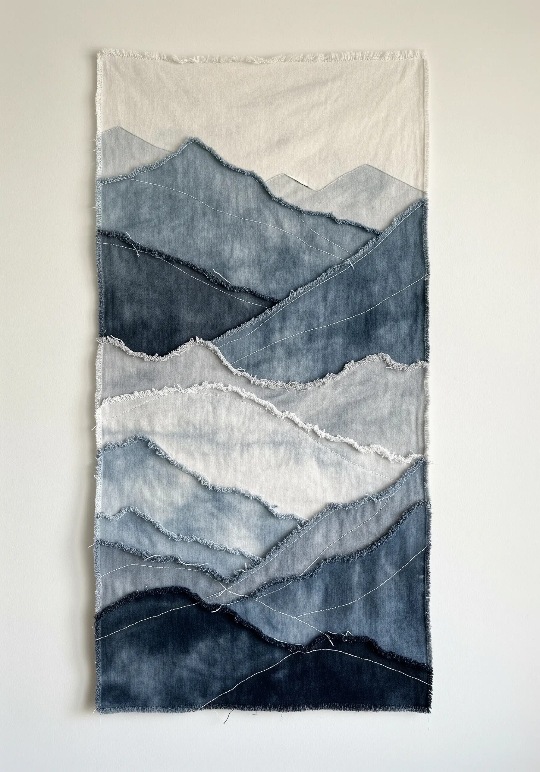 Abstract mountain landscape wall hanging made from layered, frayed denim scraps.