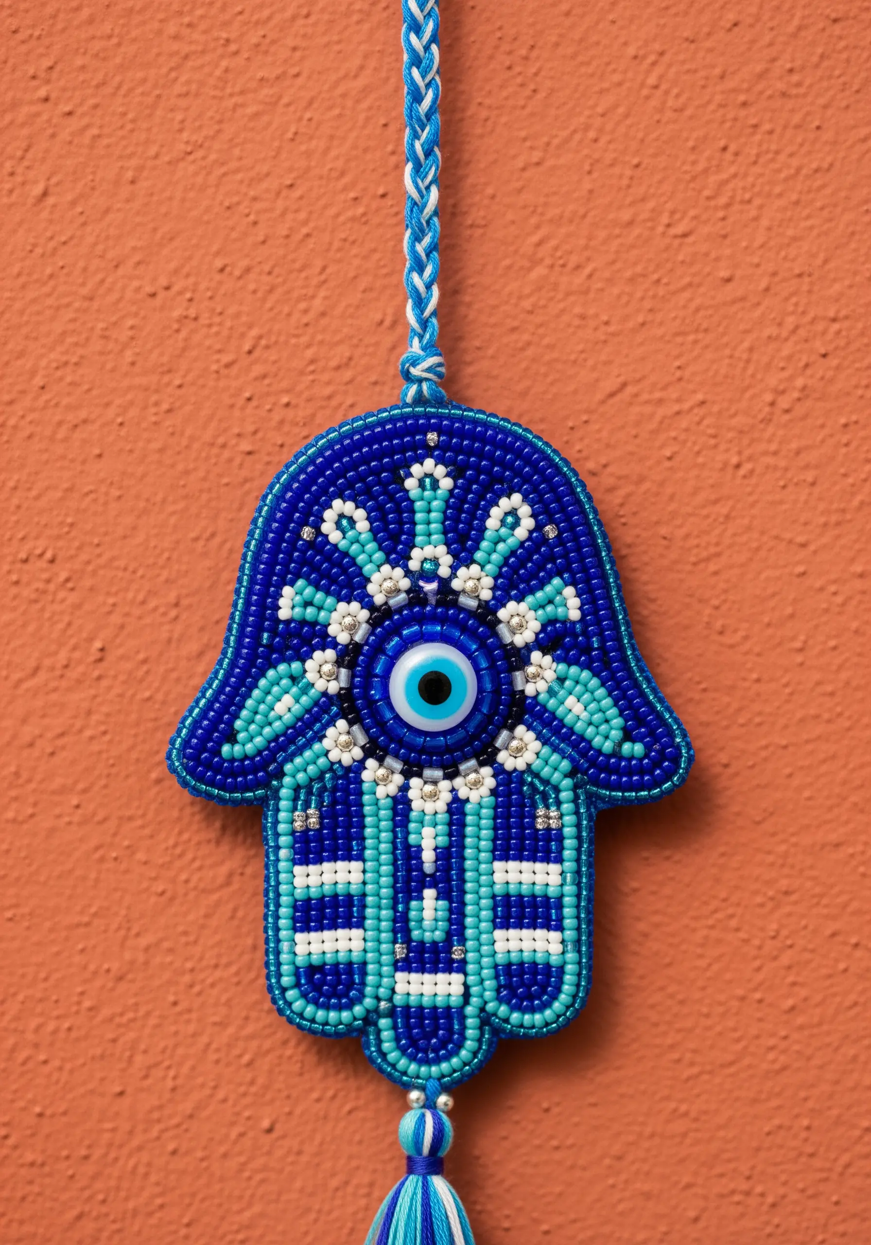 A beaded Hamsa hand wall hanging in shades of blue, turquoise, and white.