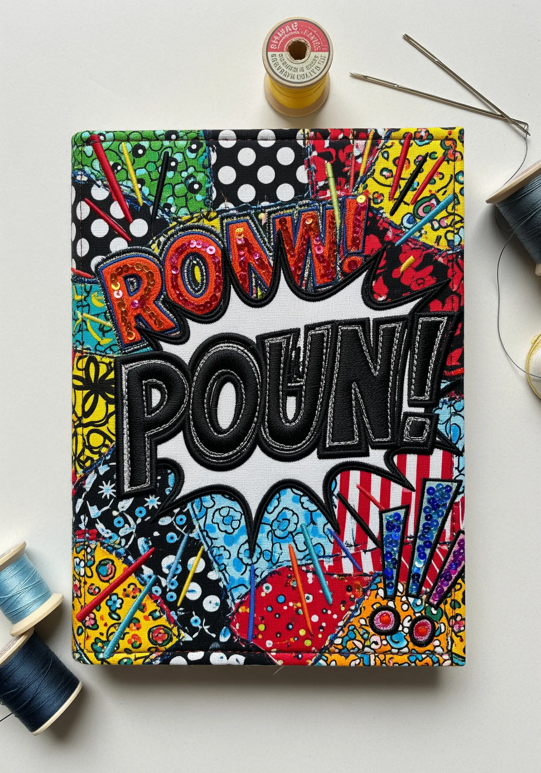 Pop art book cover with patchwork fabric, padded appliqué letters, and red sequins.