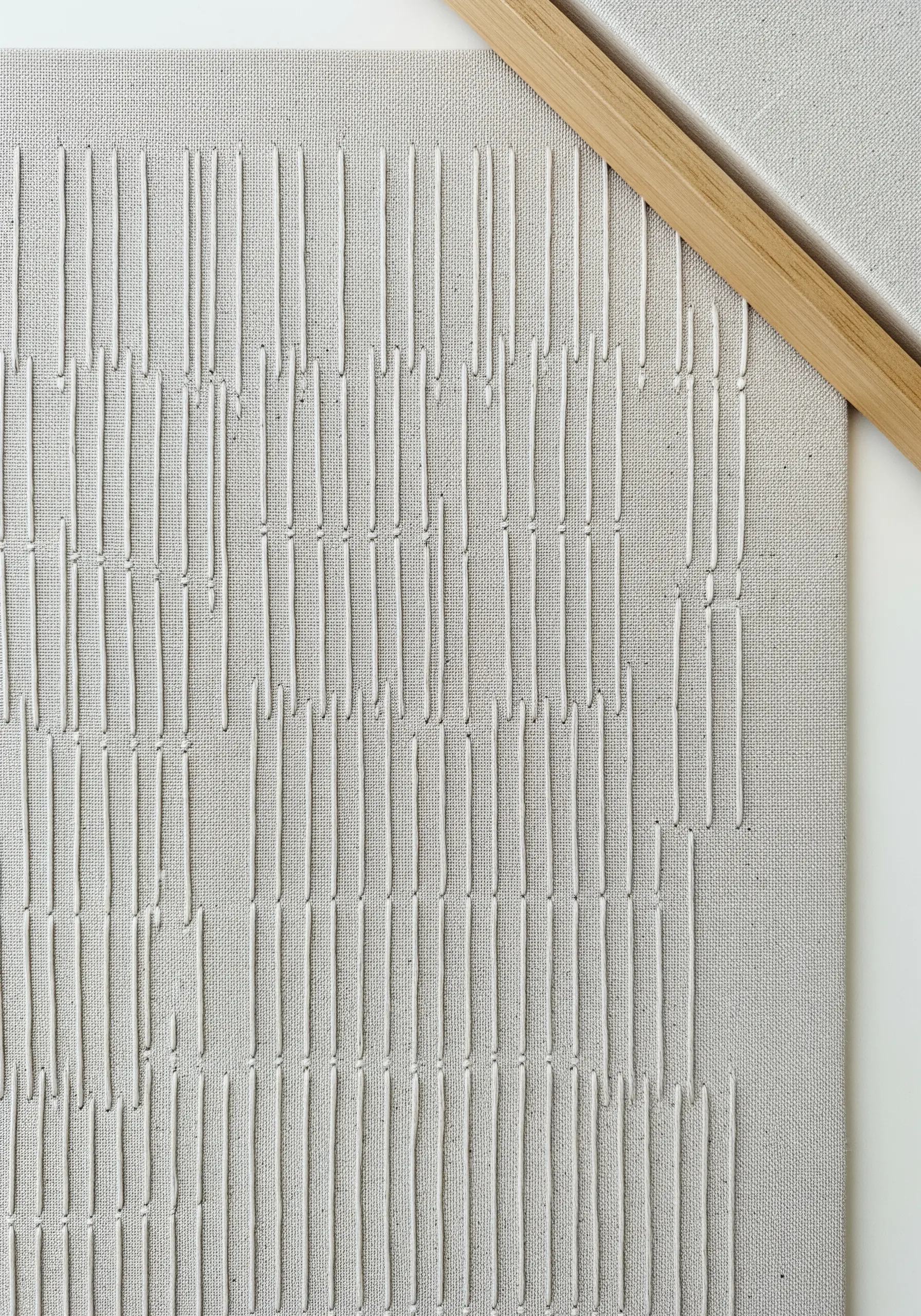 White thread stitched in vertical lines on a white canvas creates a subtle texture.