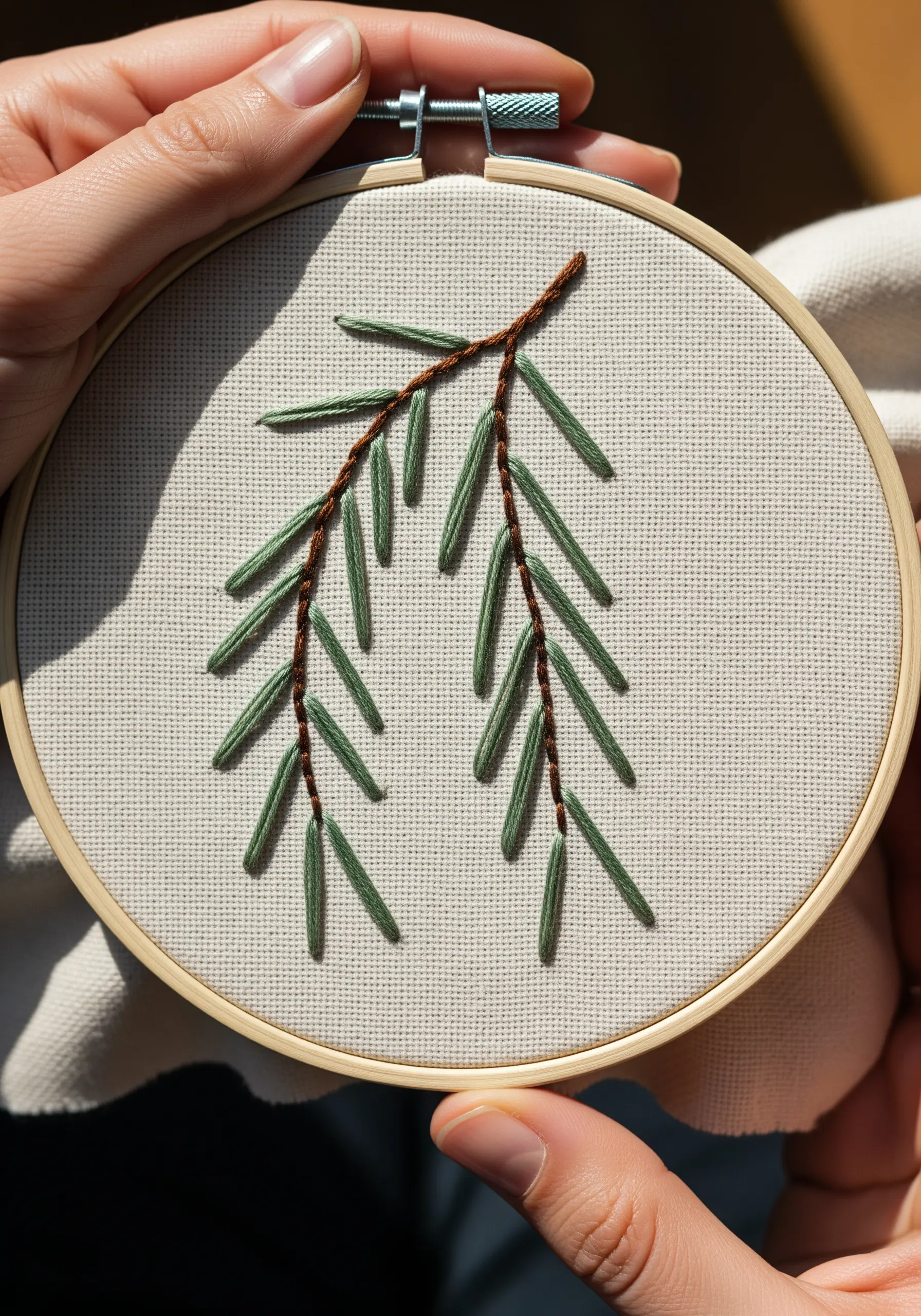 A simple pine branch with brown stem and green straight-stitch needles.