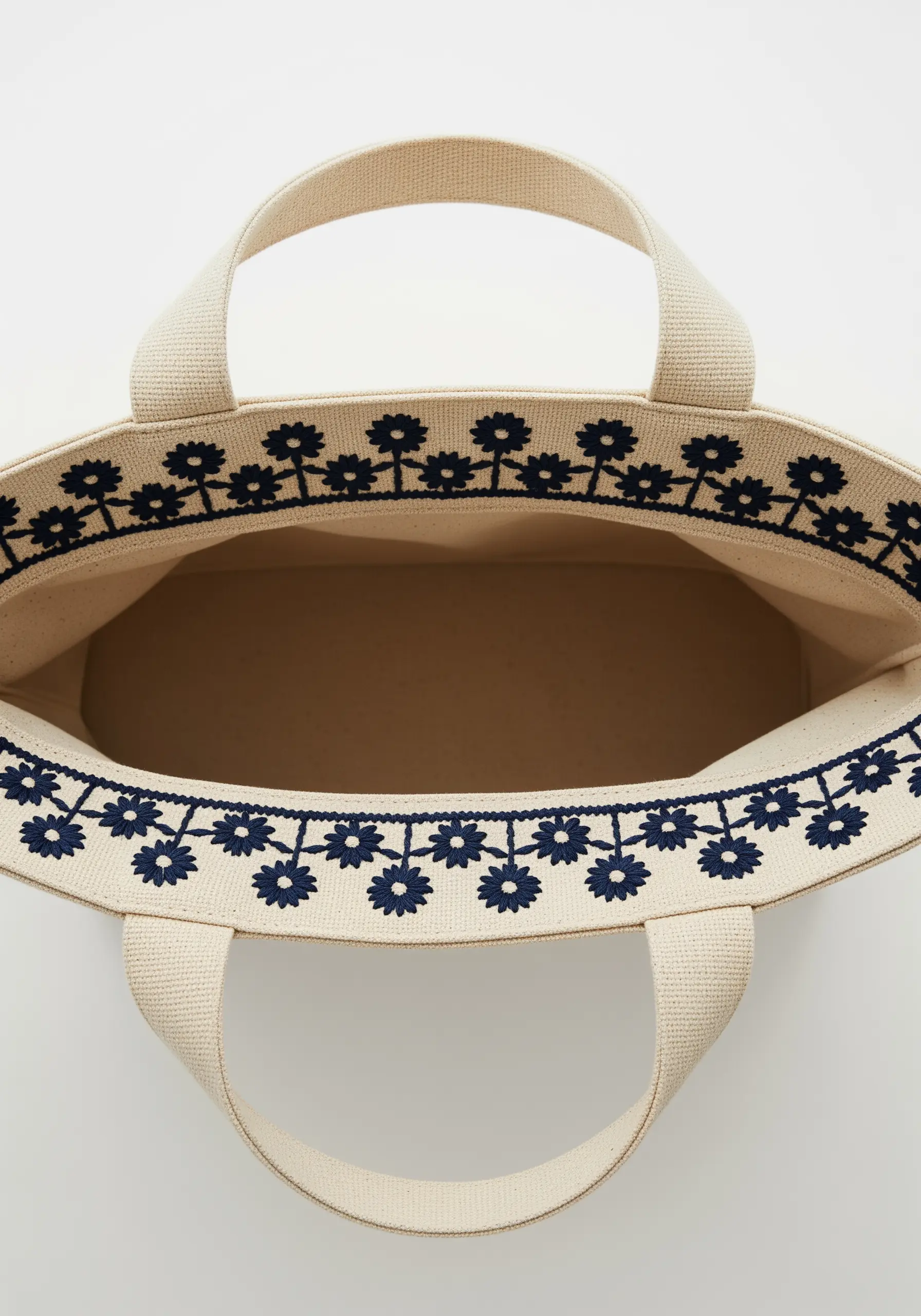 A dark blue folk-art floral border stitched along the top edge of a canvas tote.