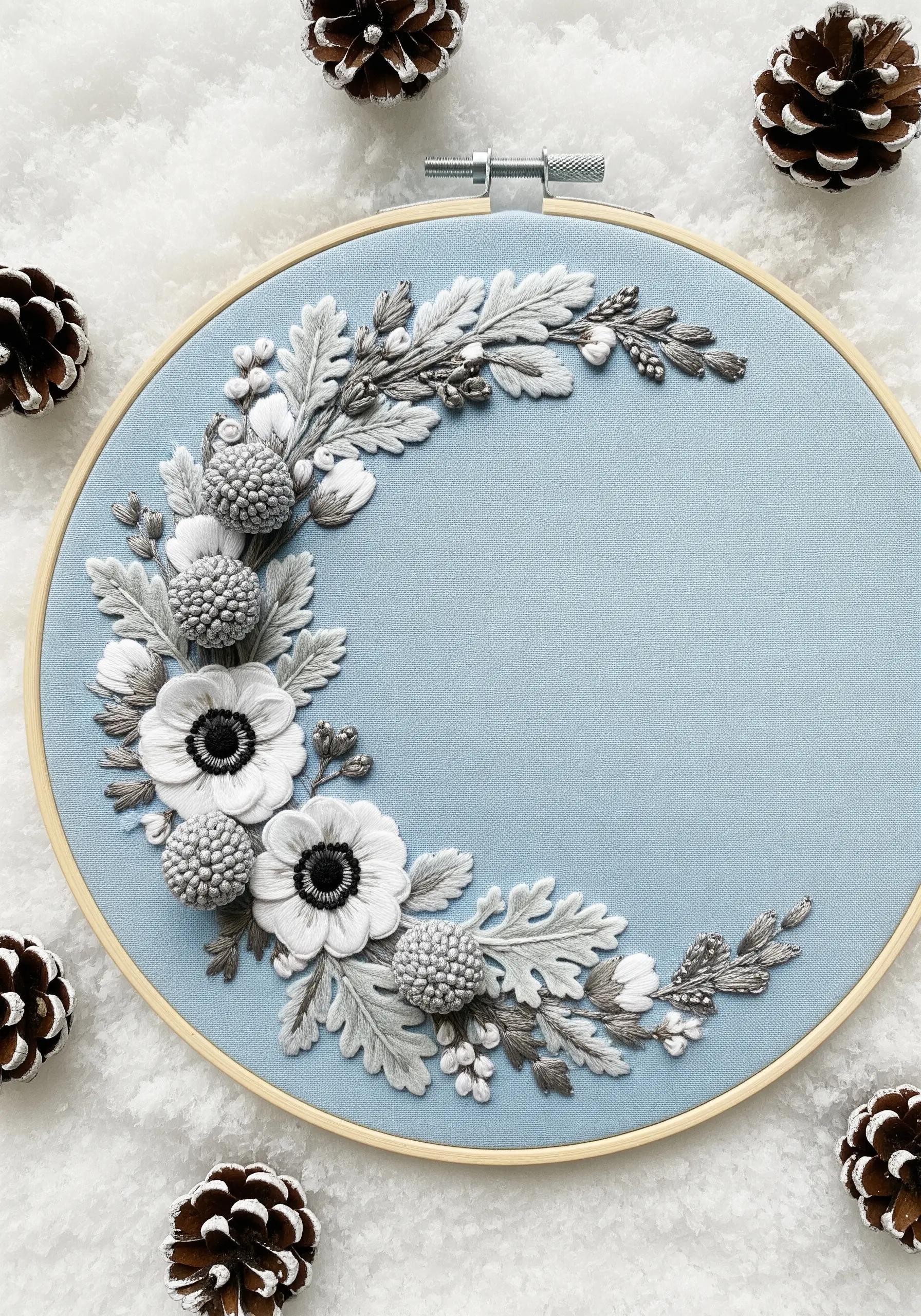 Monochromatic winter floral embroidery with white anemones and grey dusty miller on light blue fabric.