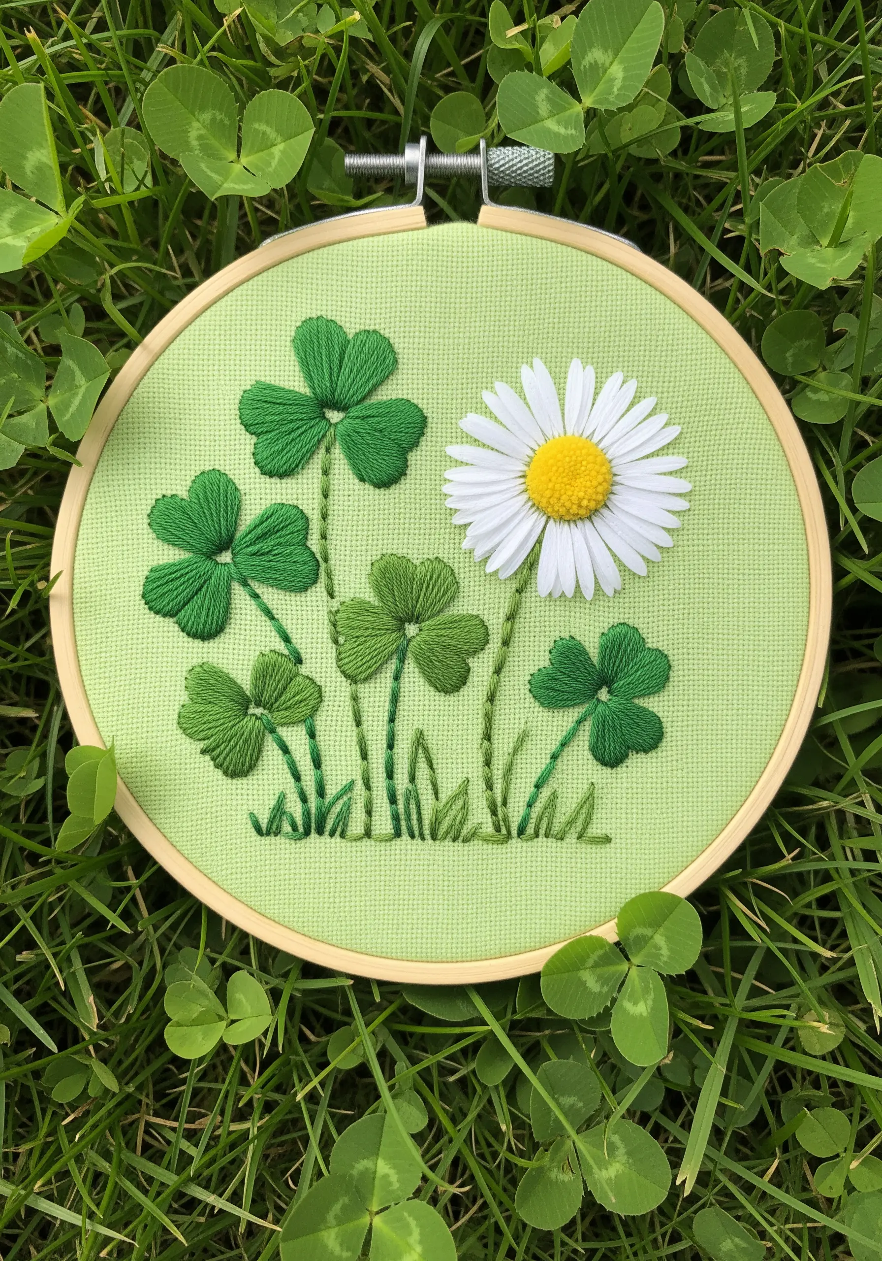 Embroidered clover and a 3D daisy with detached petals on bright green fabric.