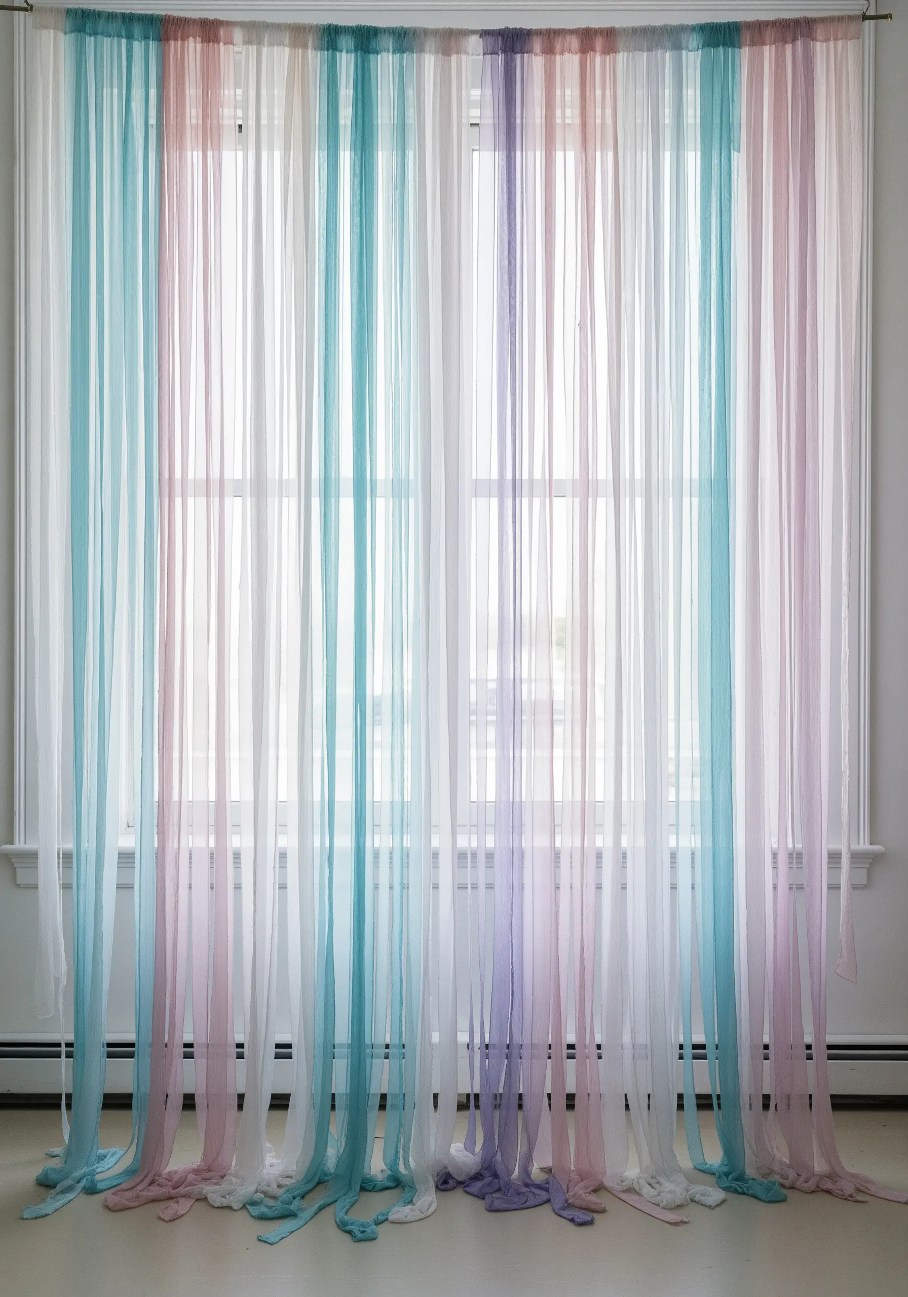 Sheer, colorful fabric strips hanging as a curtain, creating a soft, ethereal light effect.