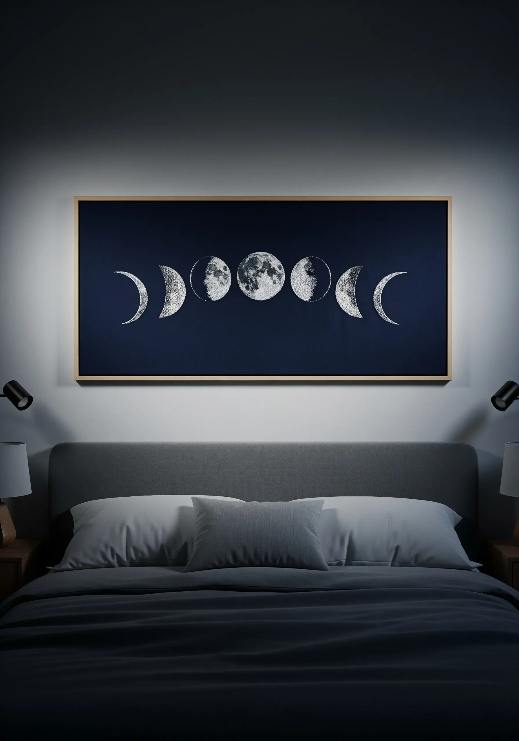A large framed textile depicting the phases of the moon with textured white embroidery.