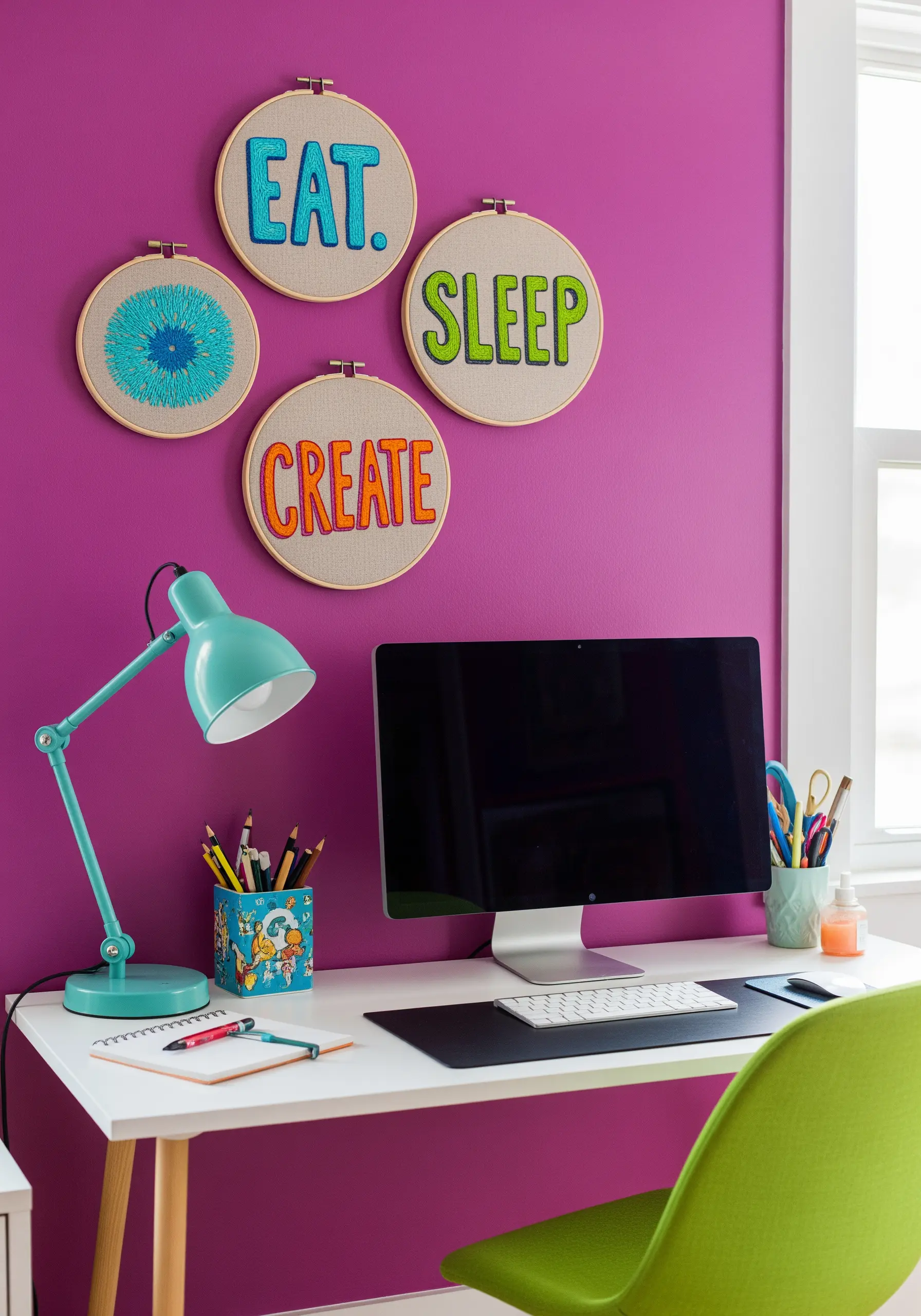 A collection of four embroidery hoops with related words and abstract designs on a bright pink wall.
