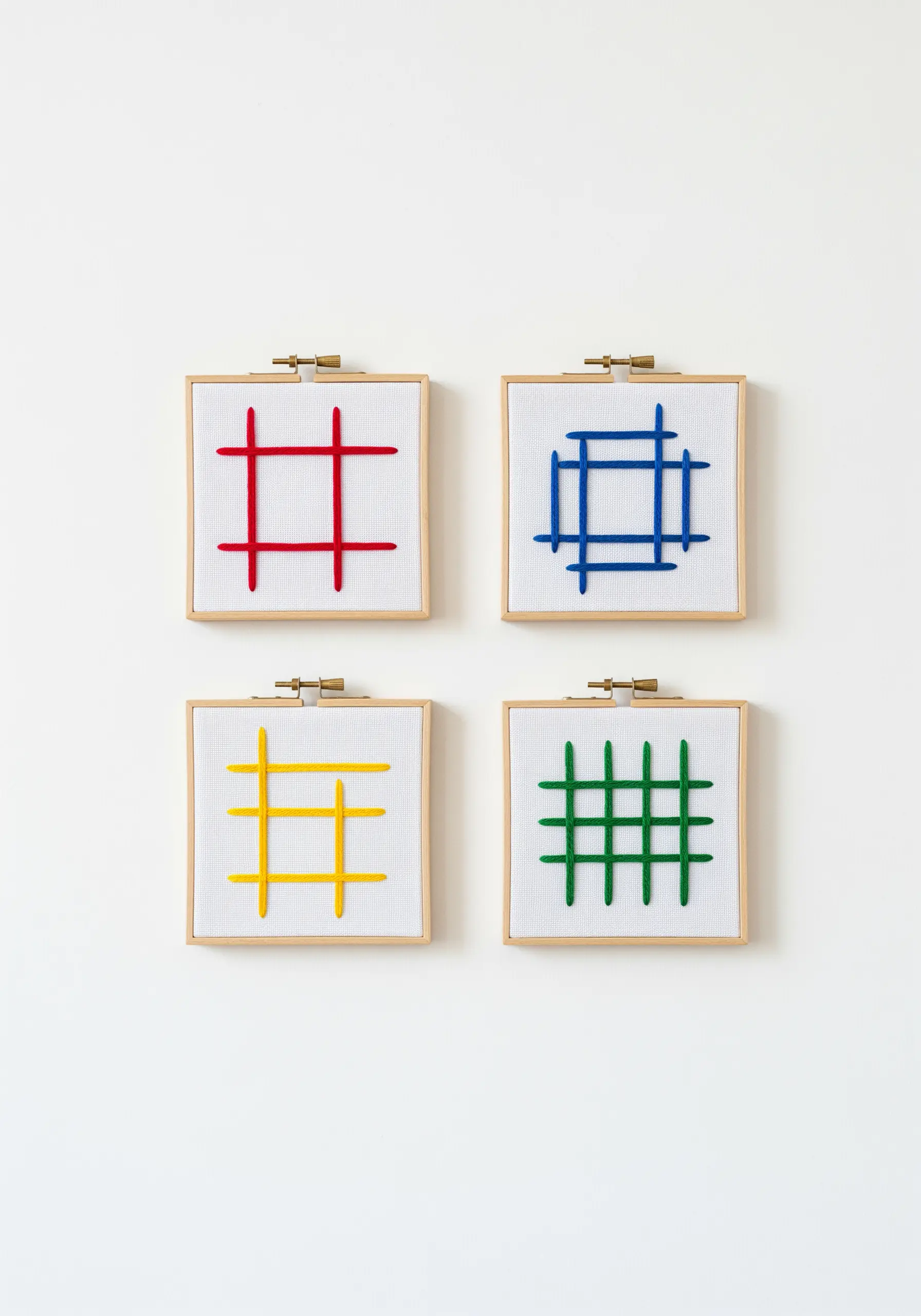 Four small framed art pieces, each with a simple grid pattern in red, blue, yellow, or green.