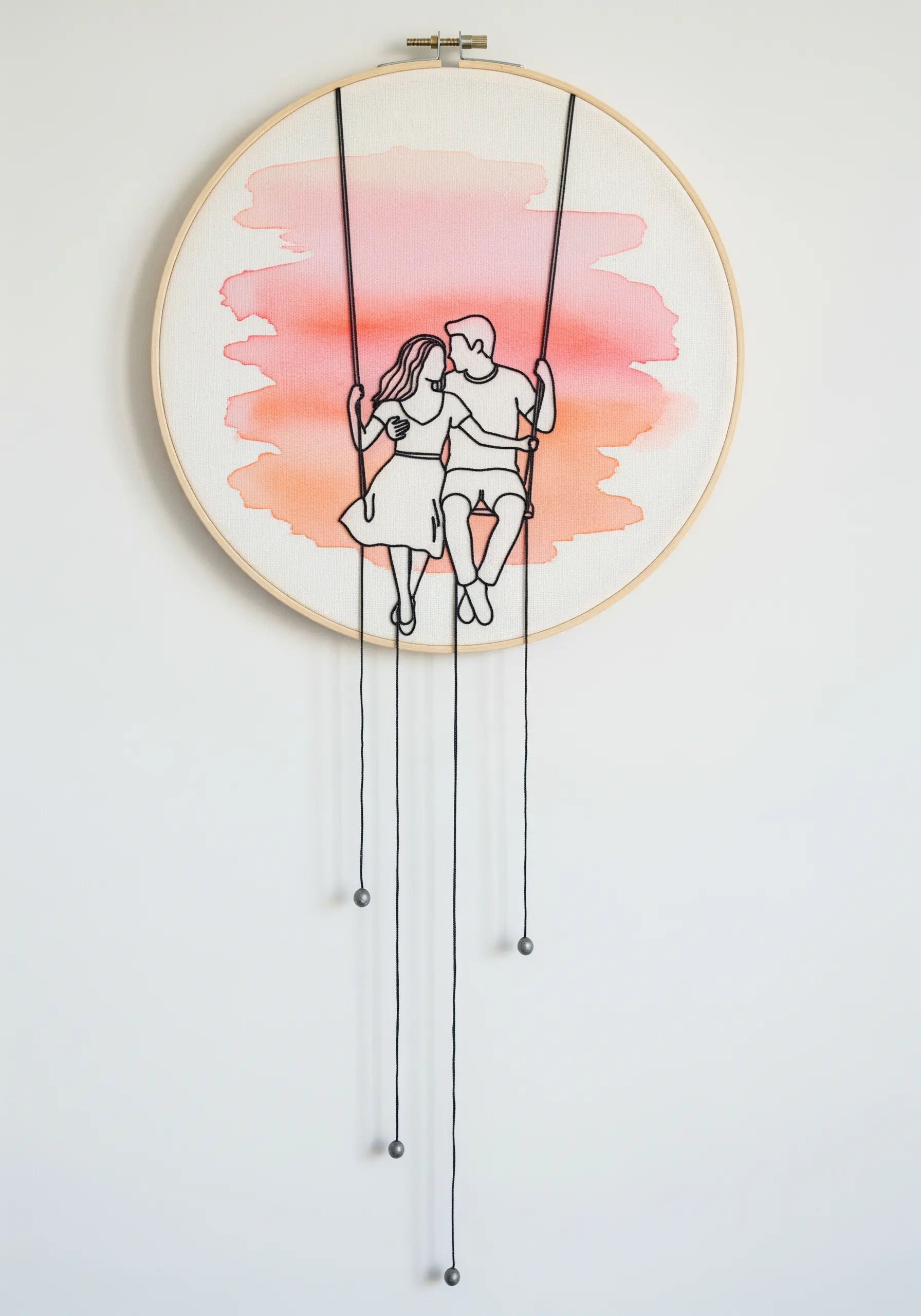 Embroidered couple on a swing against a watercolor background, with long threads hanging from the hoop.