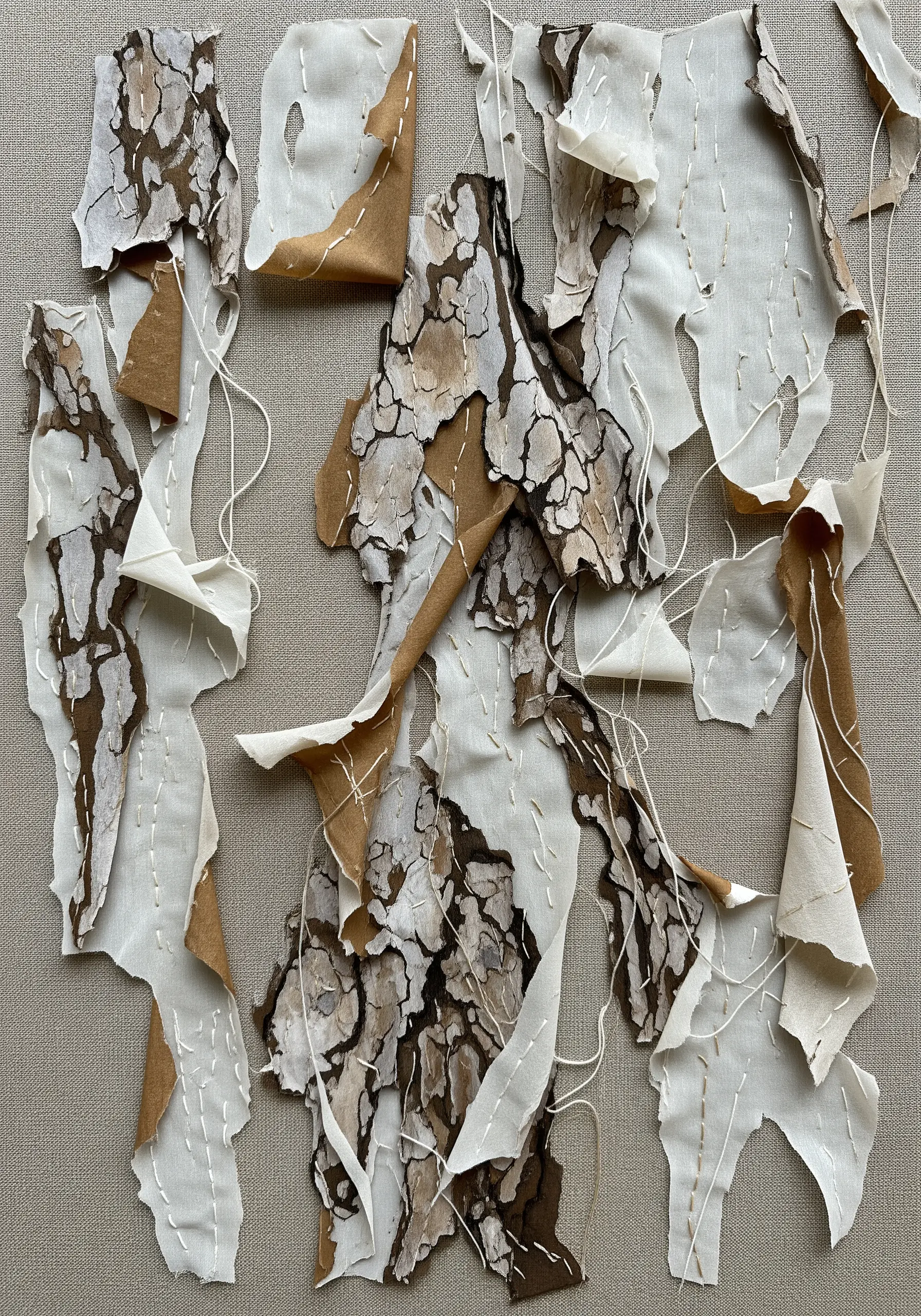Abstract textile art of peeling bark using layered and frayed pieces of fabric.
