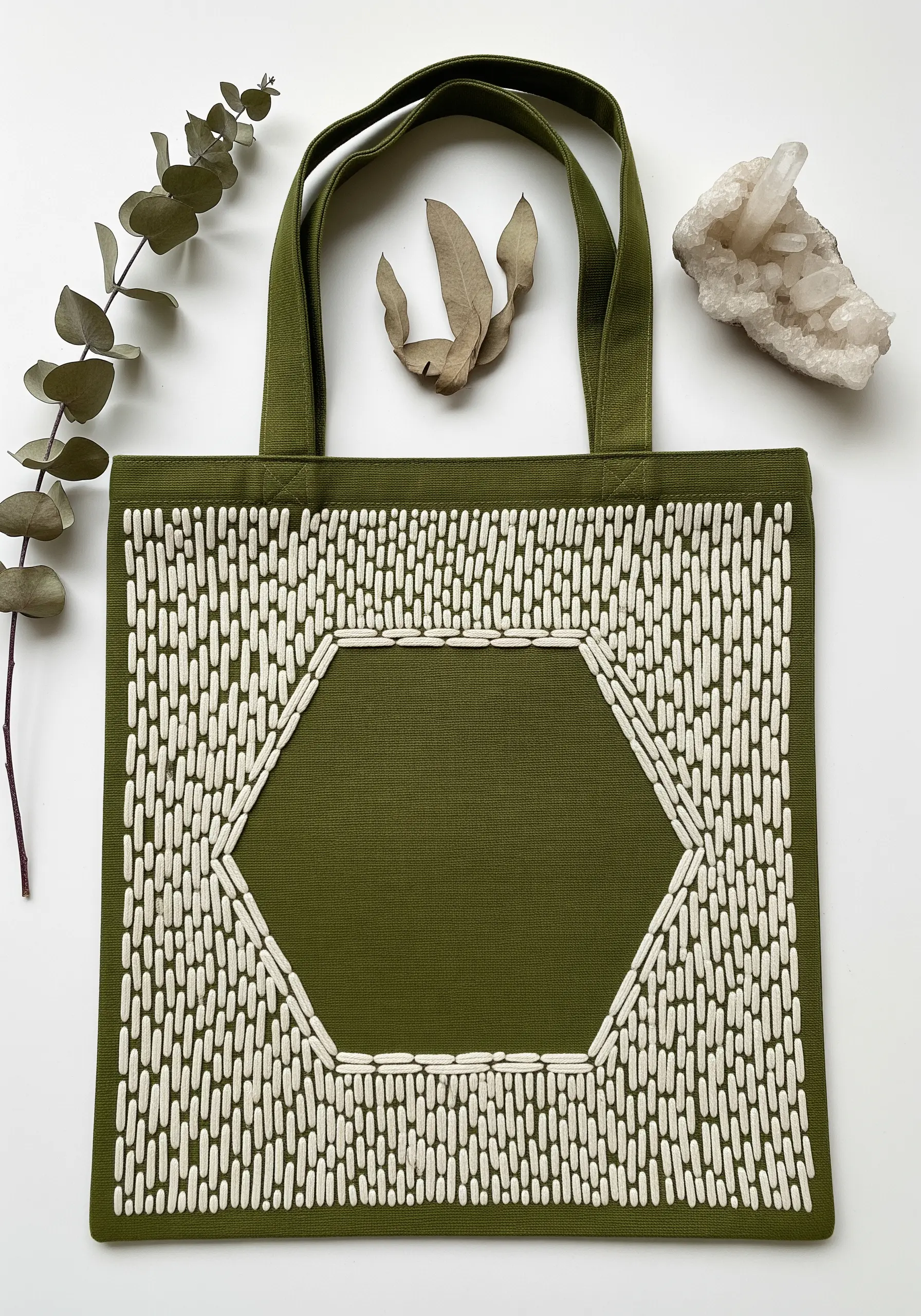 An olive green tote with a central hexagon defined by surrounding white vertical stitches.