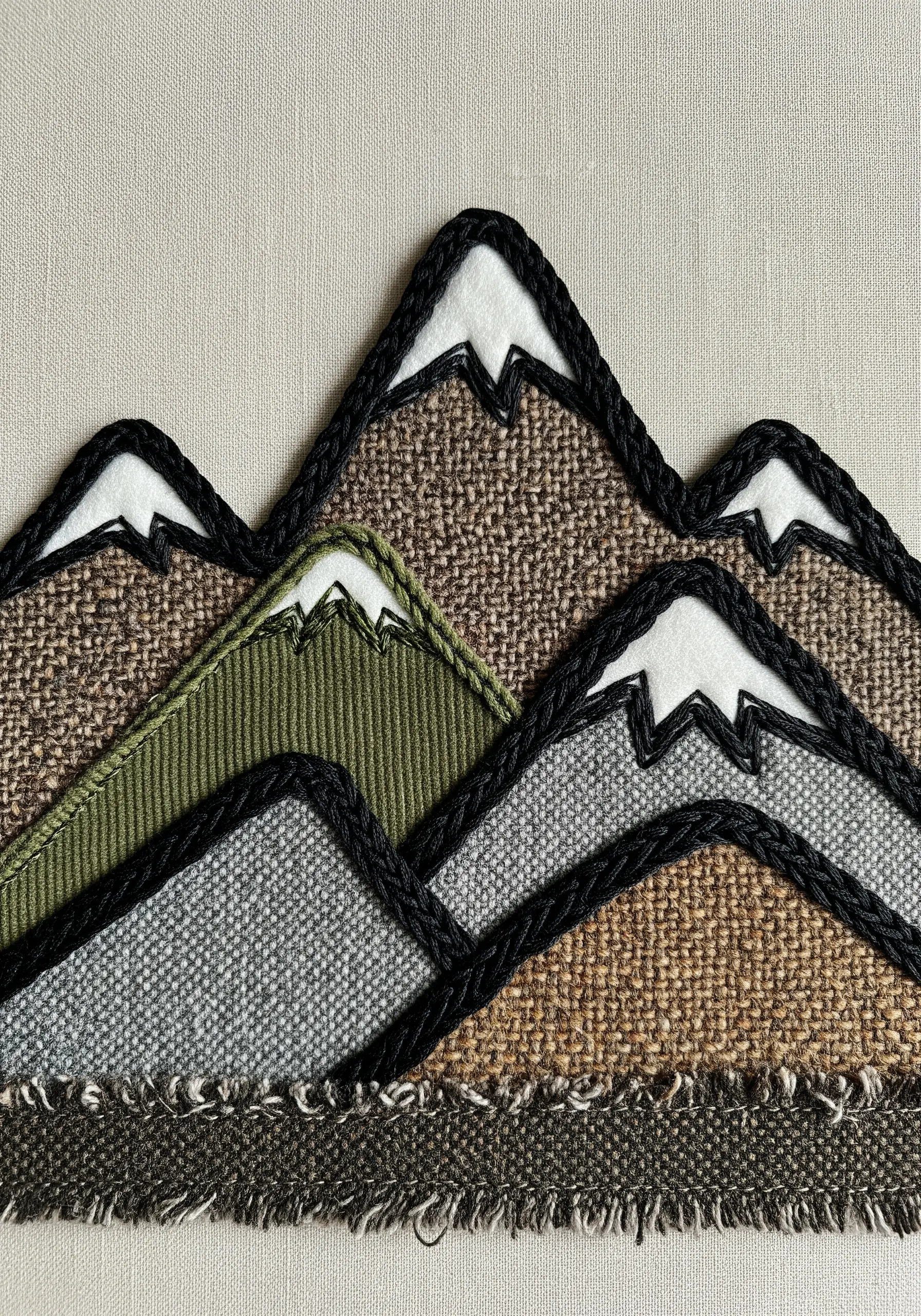 Fabric collage mountains with thick black corded outlines defining each shape.