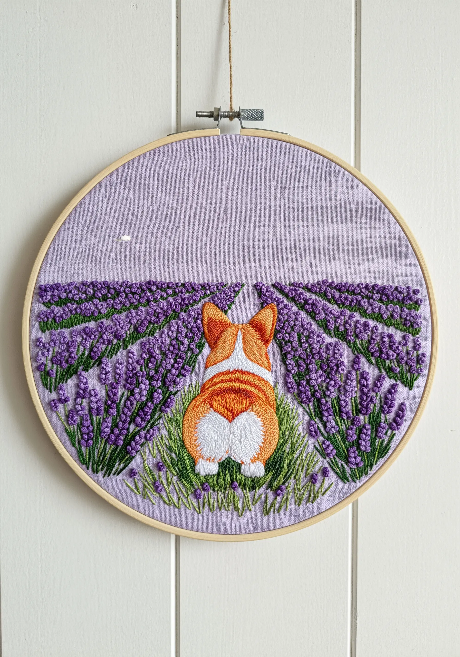 Embroidery of a Corgi from behind, looking out over a field of lavender flowers.