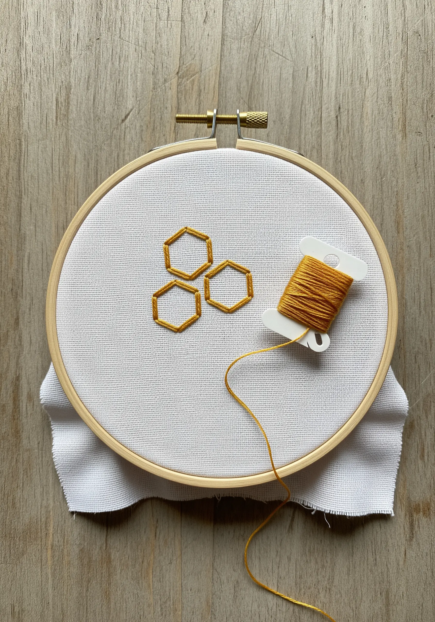 Three interlocking geometric hexagons outlined in a golden-yellow satin stitch.