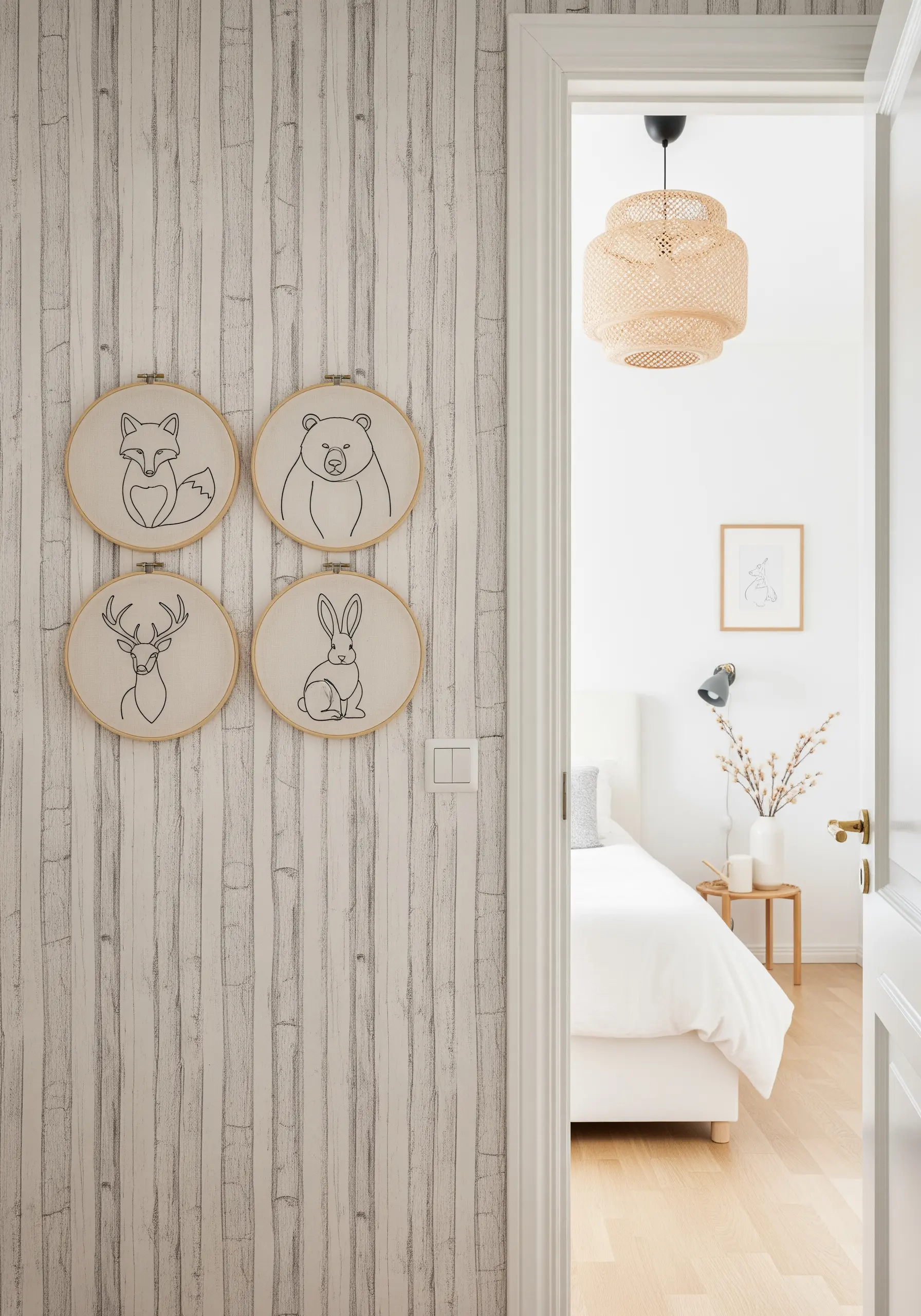 Four minimalist line-art embroidery hoops of a fox, bear, deer, and rabbit on a textured wall.
