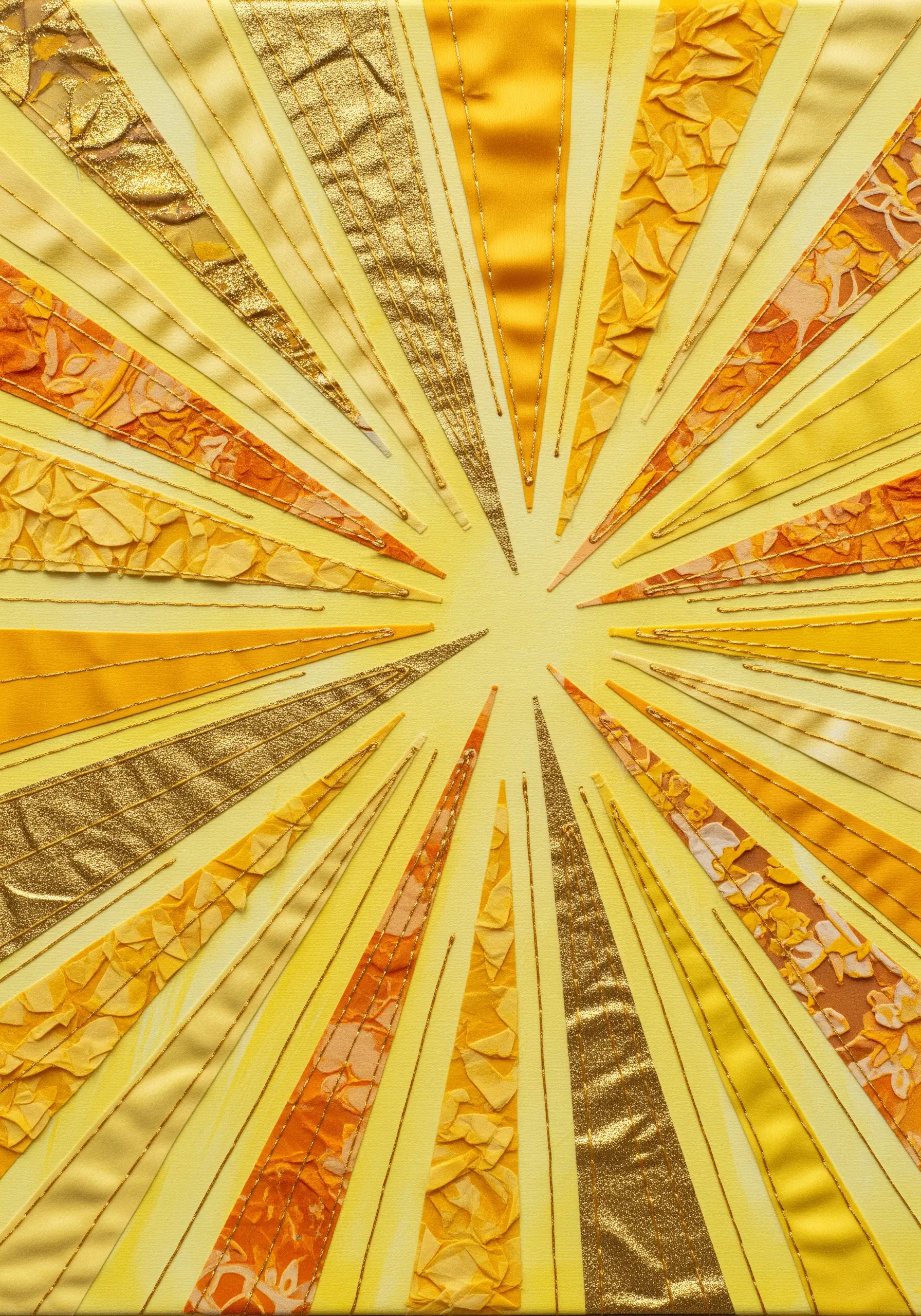 Sunburst collage made from yellow and gold fabrics, with each ray outlined in gold thread.