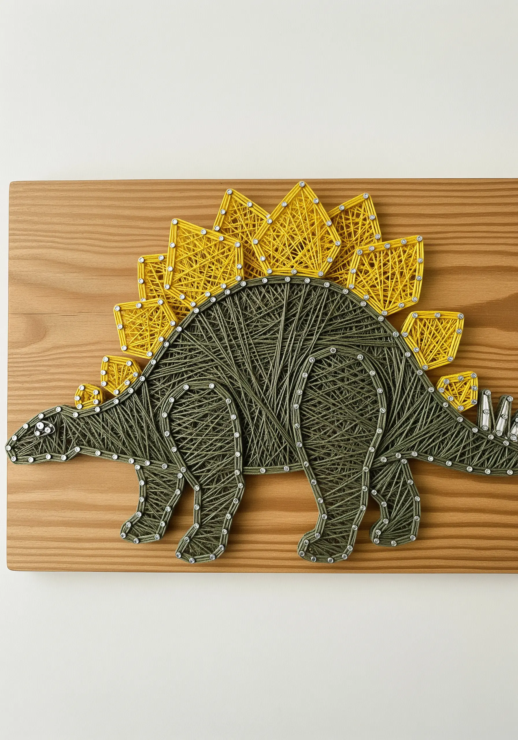 An embroidered stegosaurus with a textured green body and smooth, bright yellow back plates.