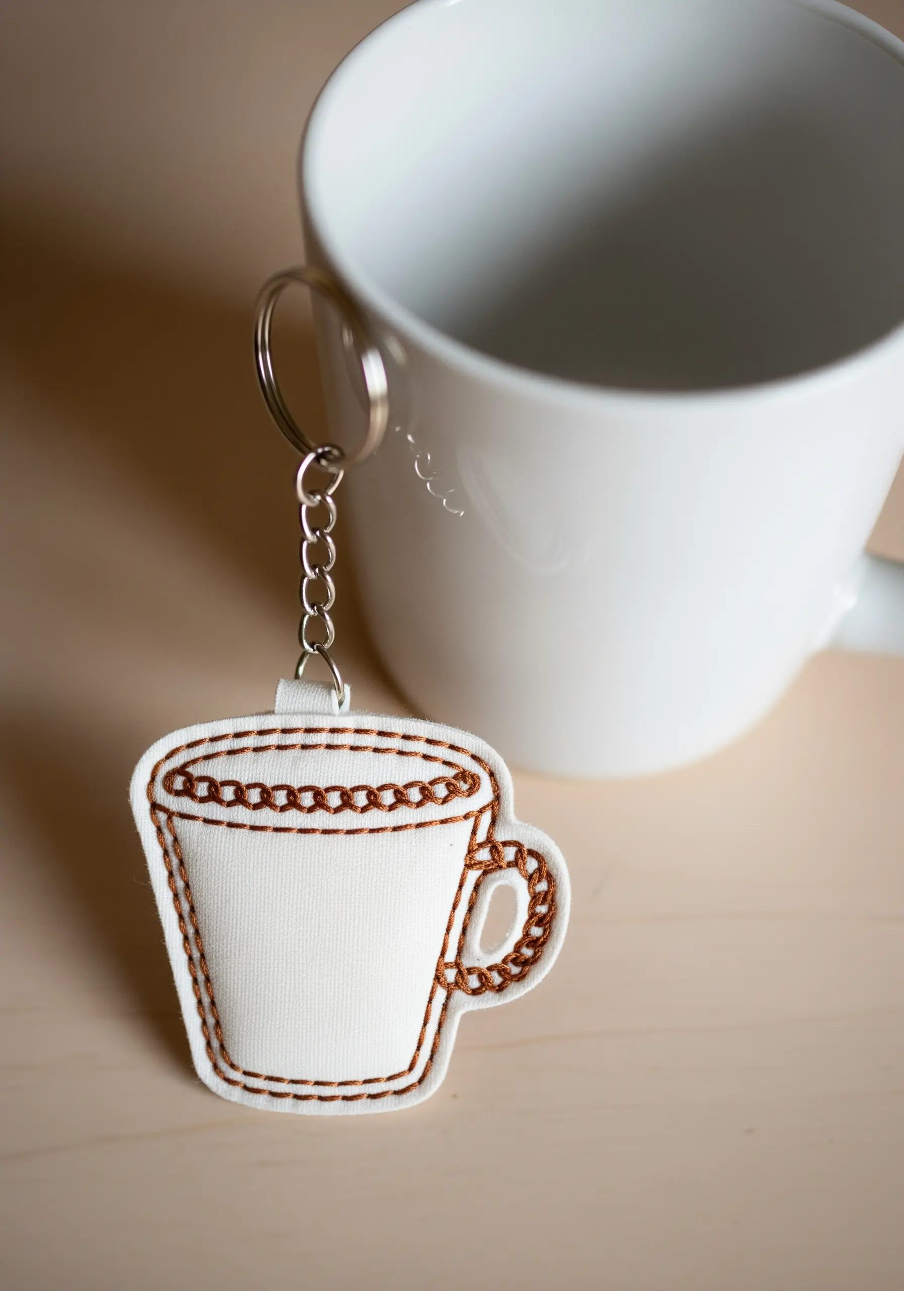 Coffee cup-shaped keychain with brown chain stitch embroidery details