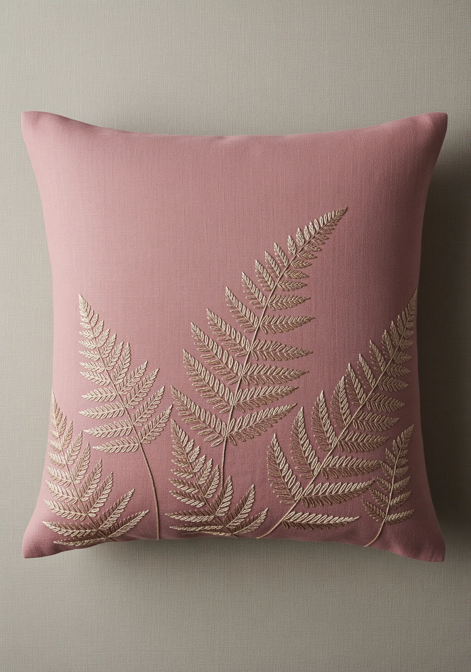 Gold thread fern leaves embroidered on a dusty pink linen cushion.