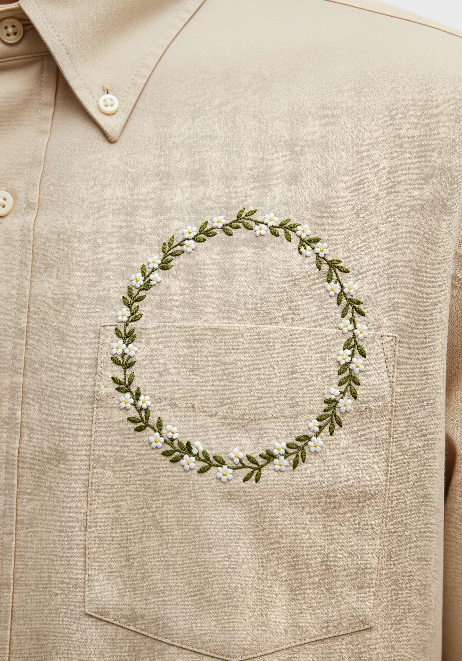 A circular wreath of small white daisies and green leaves framing a shirt pocket.