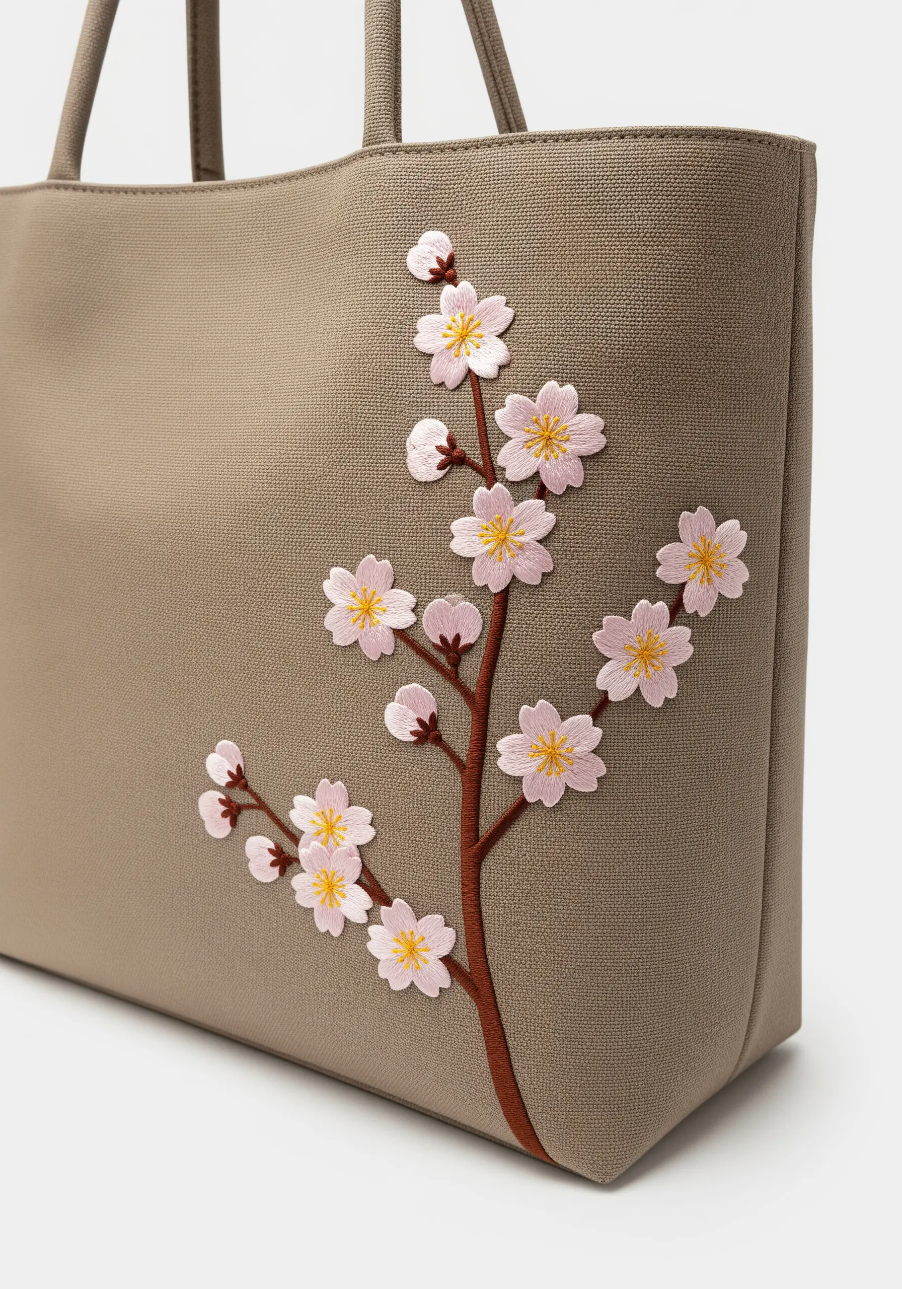 A branch of delicate pink and white cherry blossoms on a taupe tote bag.