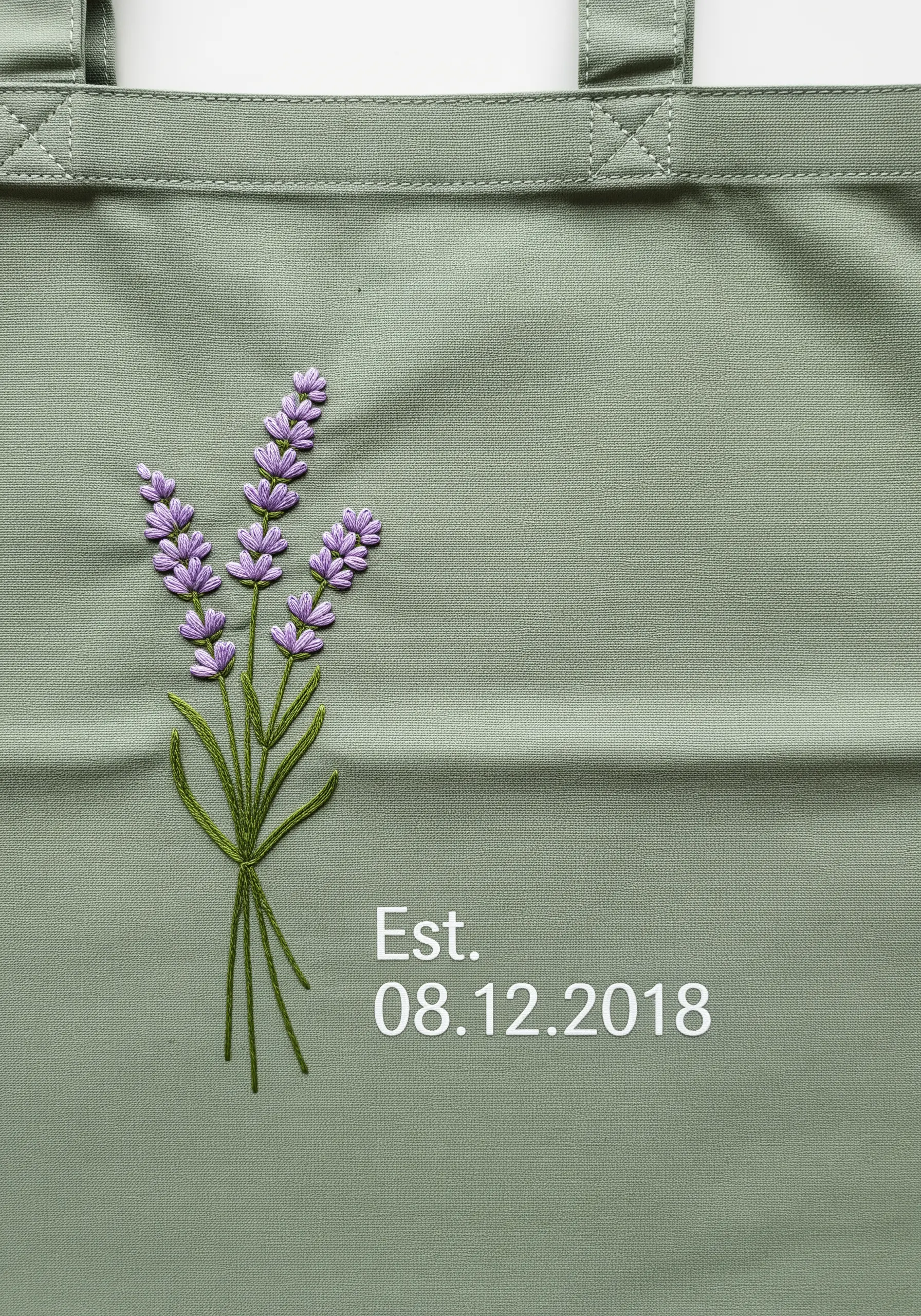 Embroidered lavender sprigs with a personalized anniversary date on a sage green tote bag.