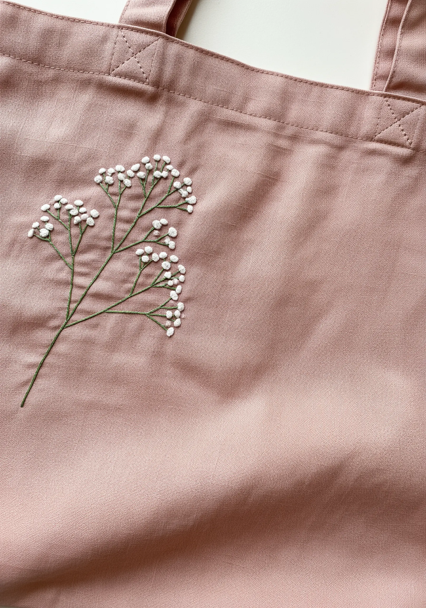 A delicate sprig of Baby's Breath embroidered with French knots on a pink tote.
