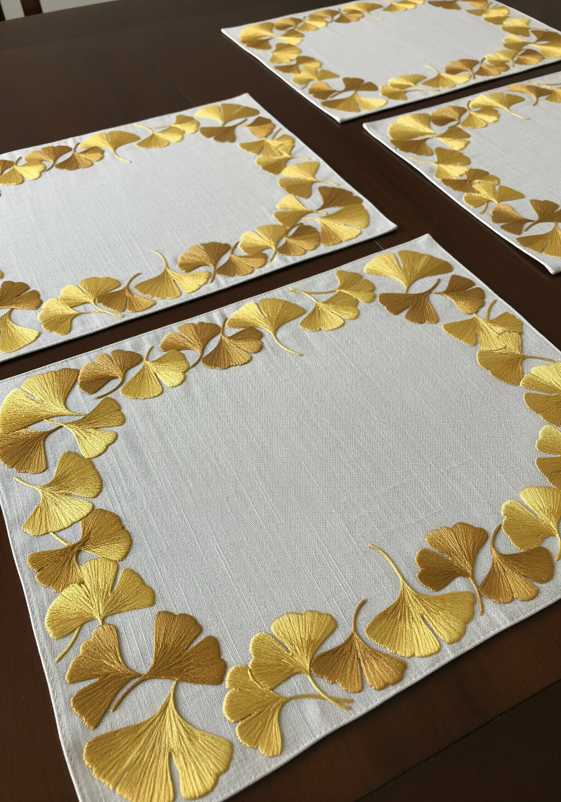 Placemat with a border of ginkgo leaves embroidered in shiny gold metallic thread.