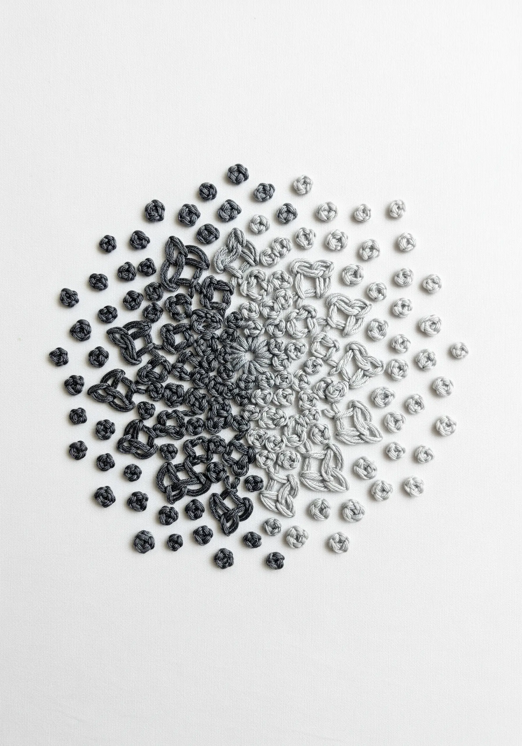 A monochrome mandala made of knots transitioning from dense black to sparse grey.
