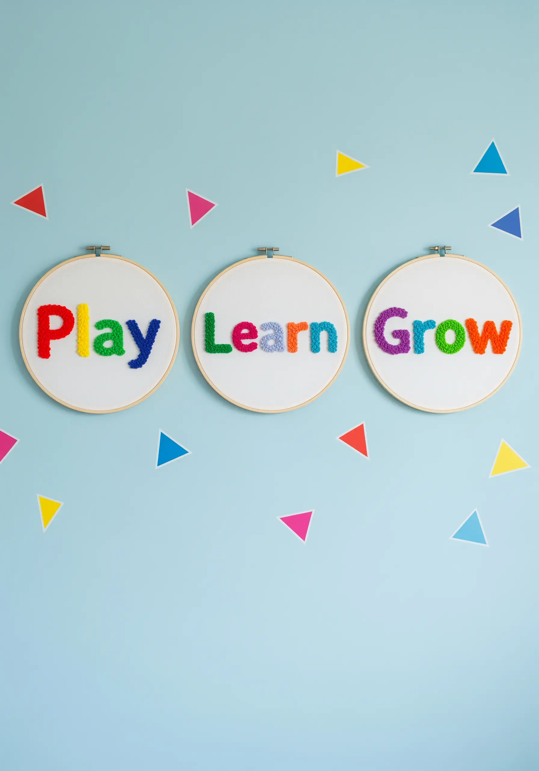 Three embroidery hoops, each with a single word filled with colorful French knots.