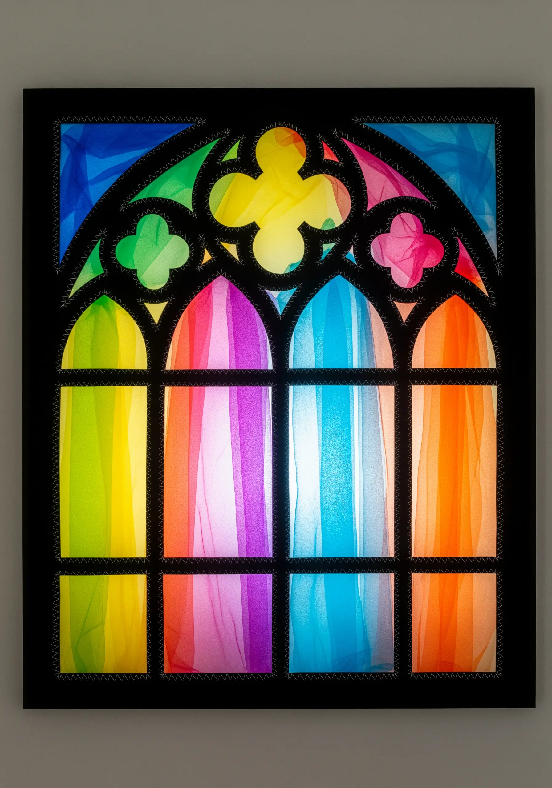 A textile art piece resembling a stained-glass window, using black felt and colorful sheer fabrics.