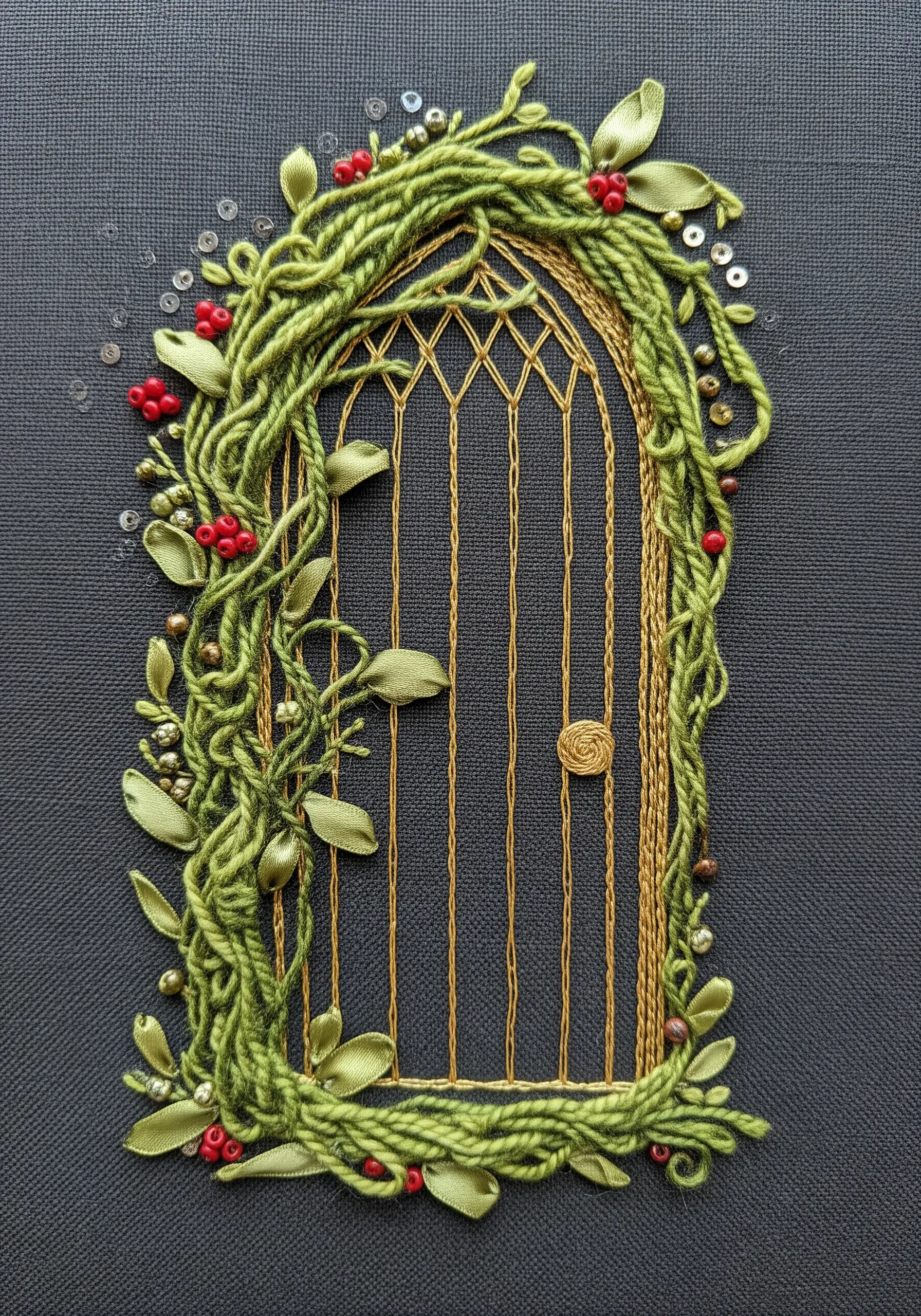 A golden embroidered door wrapped in green couched yarn, ribbon leaves, and red beads.