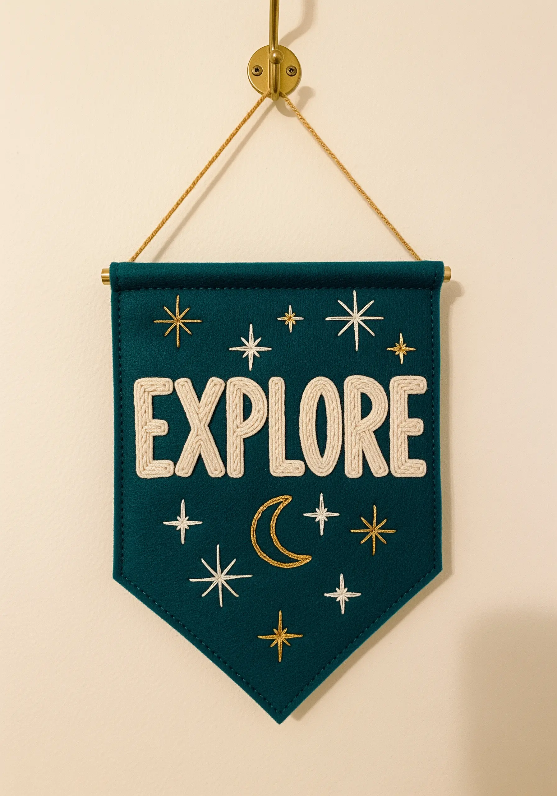 A dark teal felt banner with the word 'EXPLORE' couched in thick white yarn and gold stars.