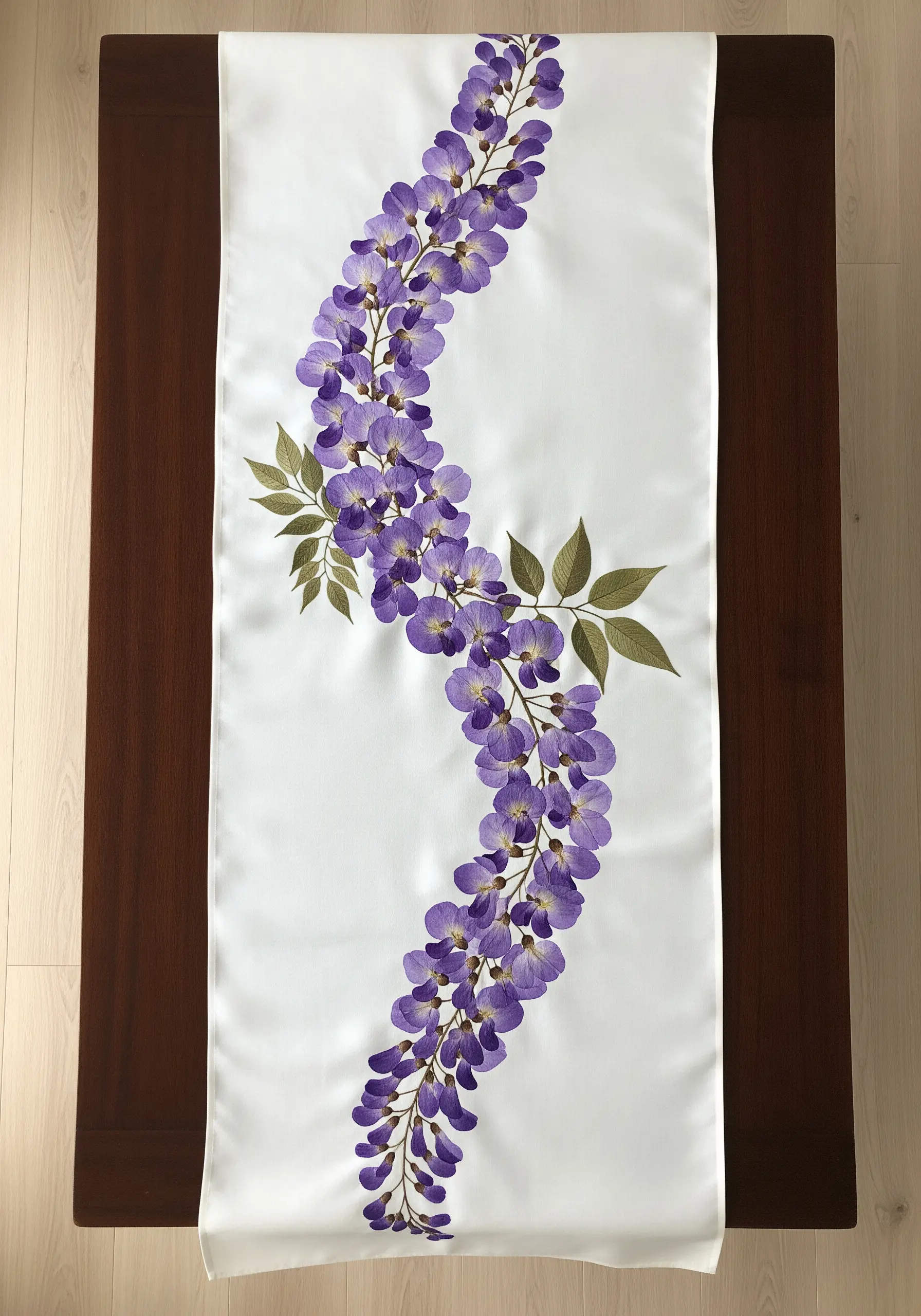 A white table runner with a flowing, S-shaped embroidery of a wisteria vine.