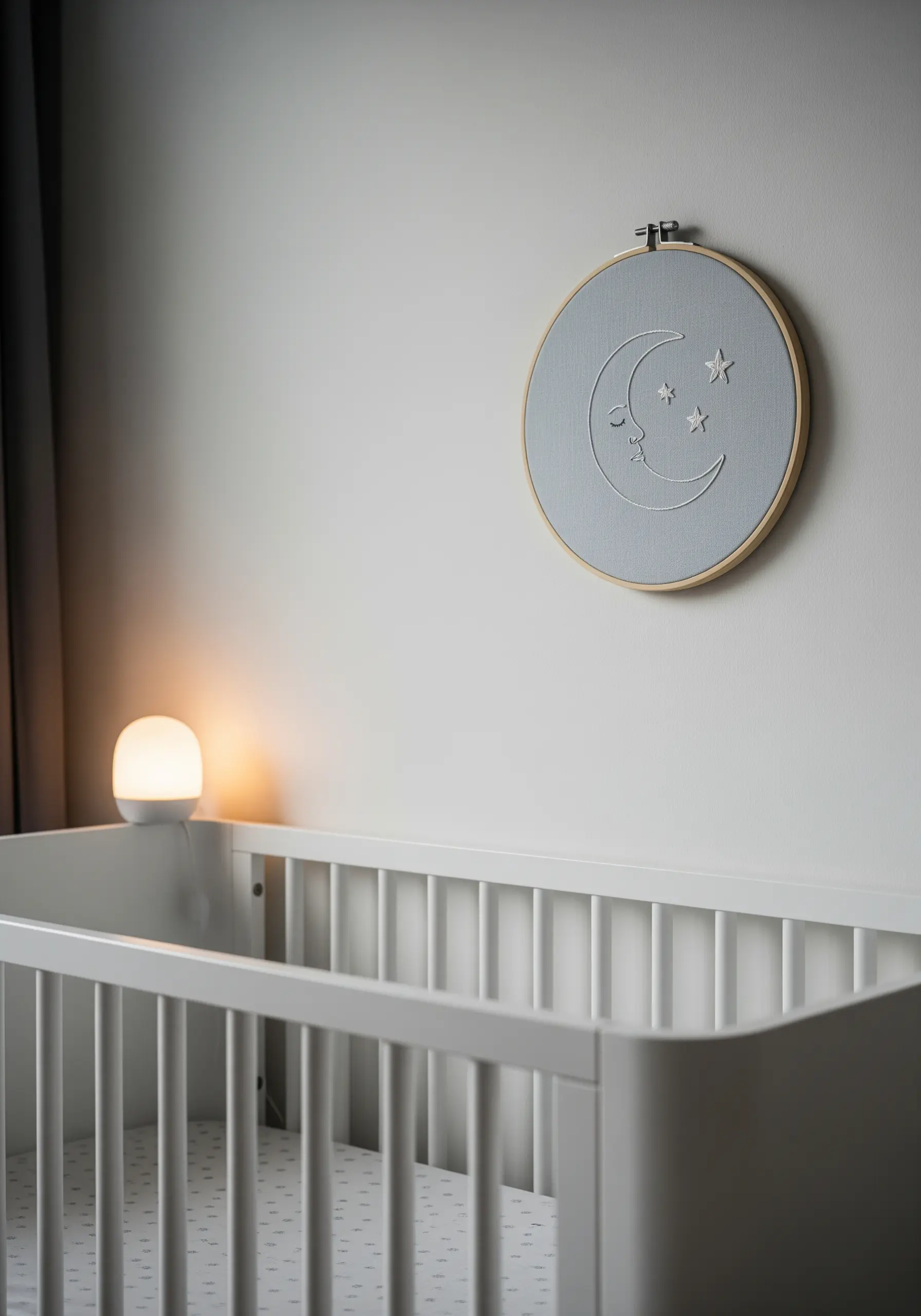 A calming embroidery hoop with a crescent moon and stars, stitched in white on blue fabric.