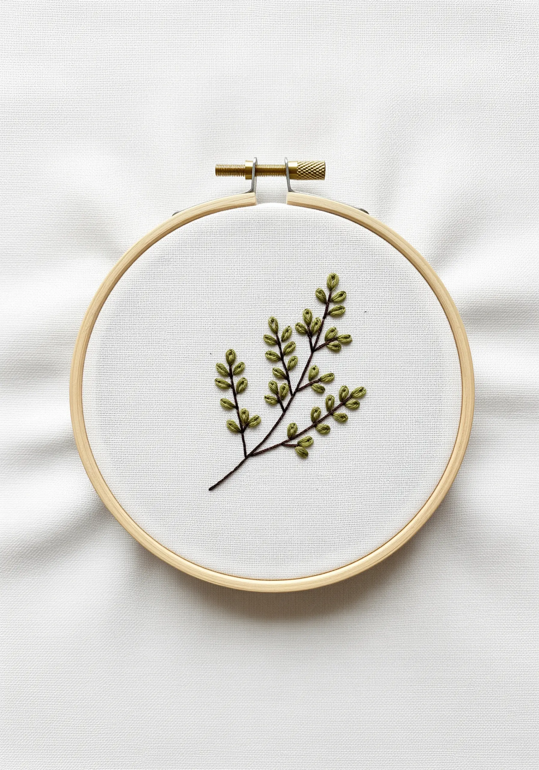 A delicate embroidery of a thyme sprig with tiny, padded green leaves.