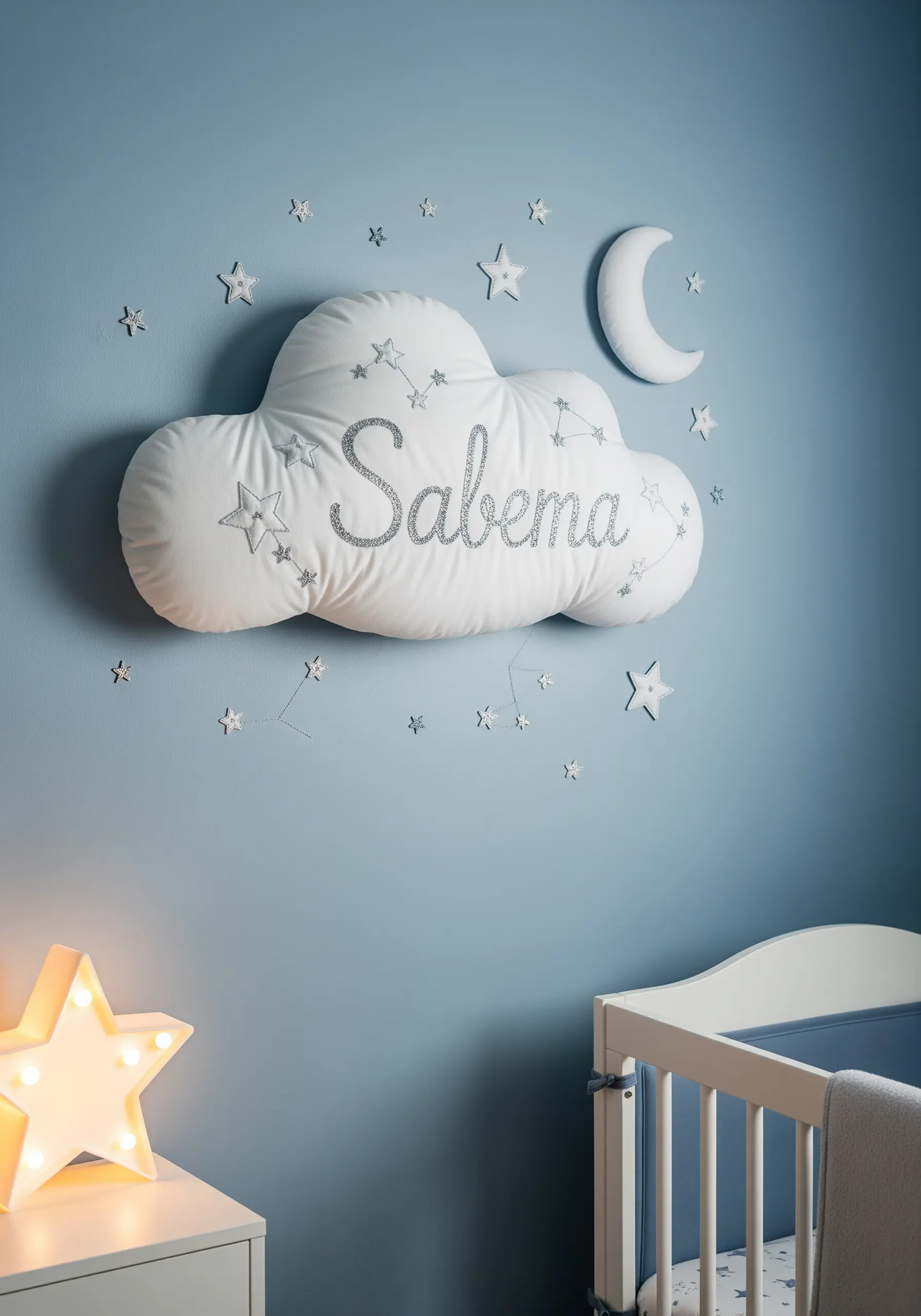 A plush, cloud-shaped pillow with a name embroidered in silver thread.