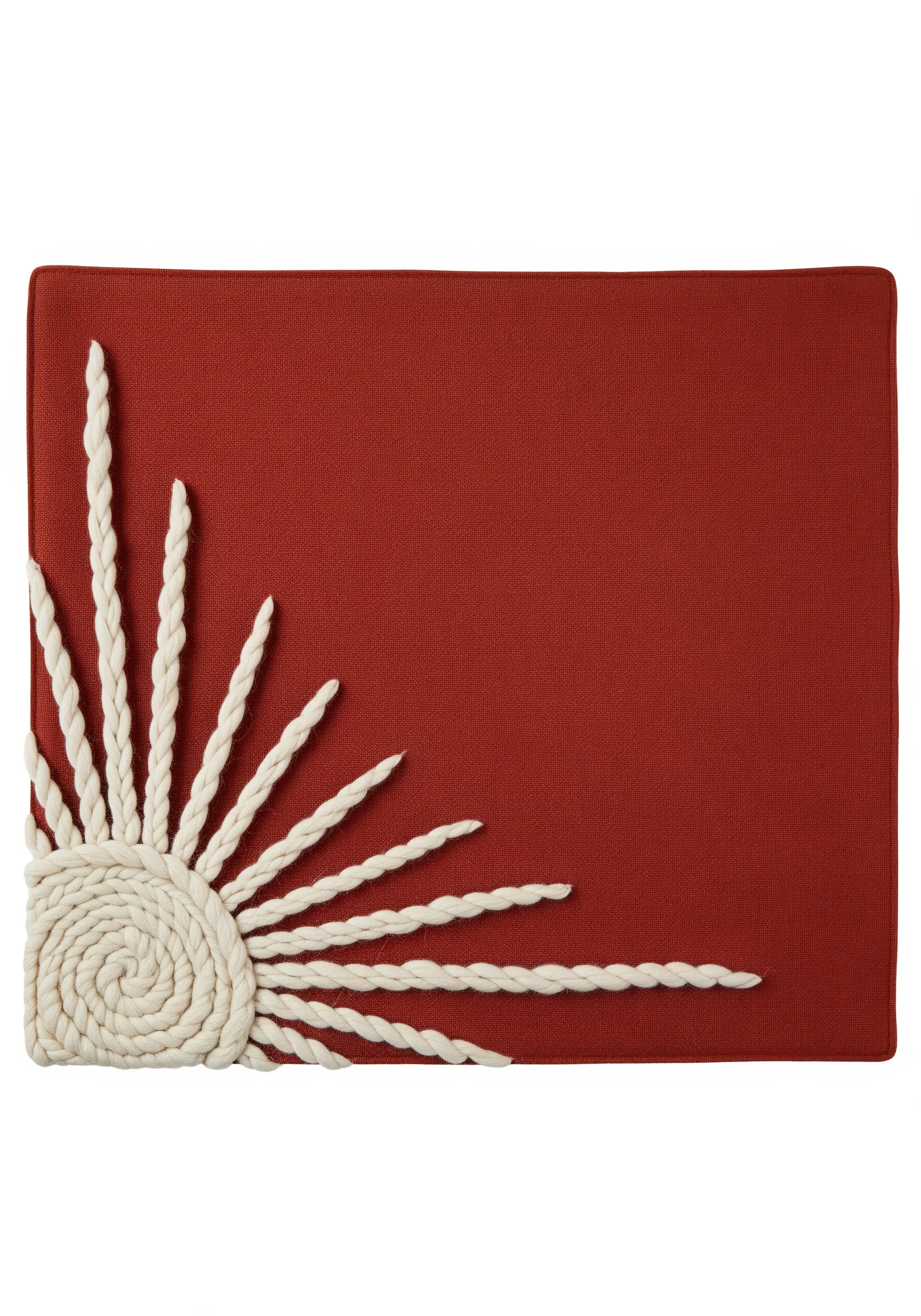 A sun motif on a terracotta placemat made from thick, couched white cotton rope.